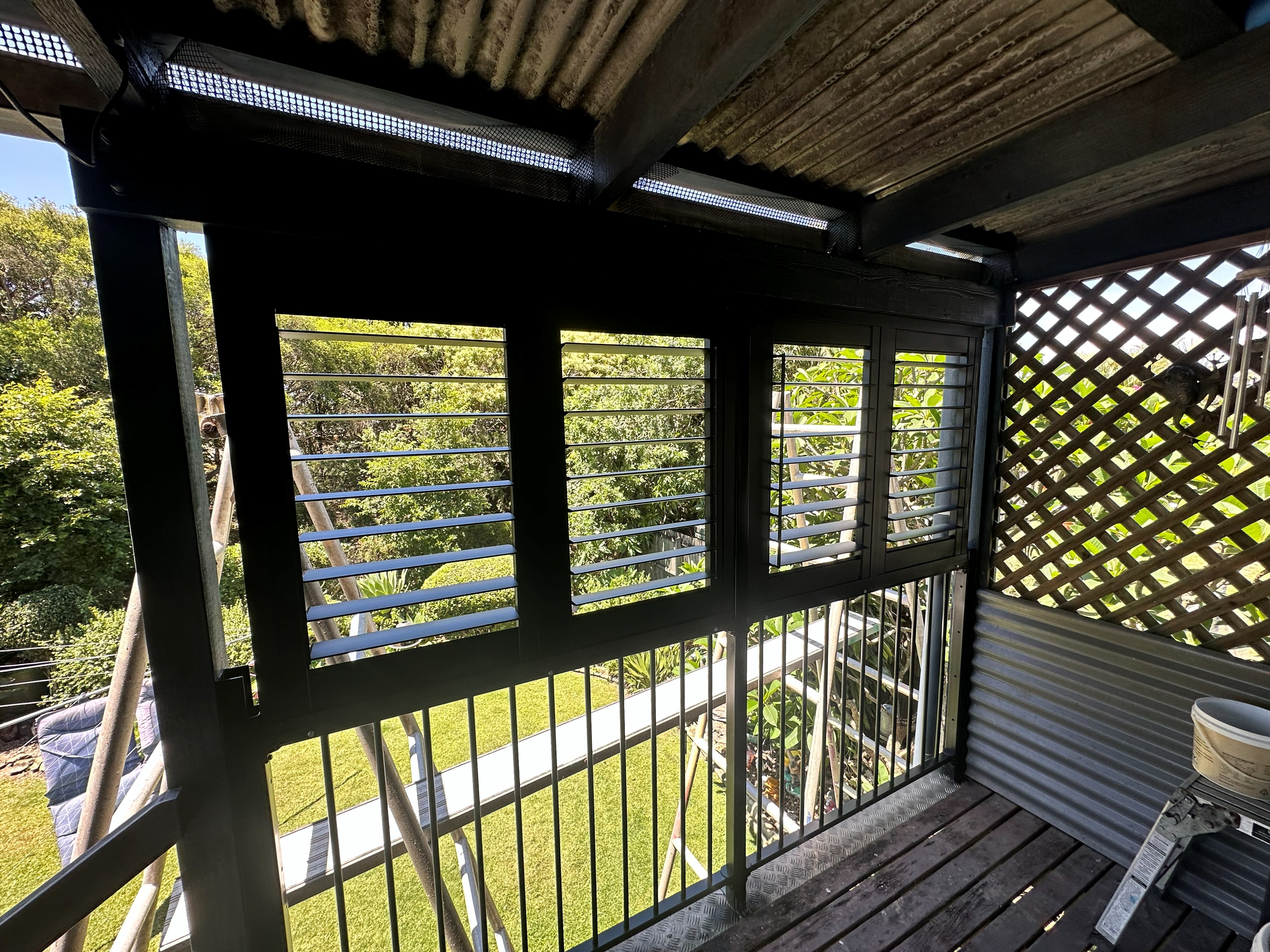 White aluminium shutters fitted along a wraparound Queenslander verandah