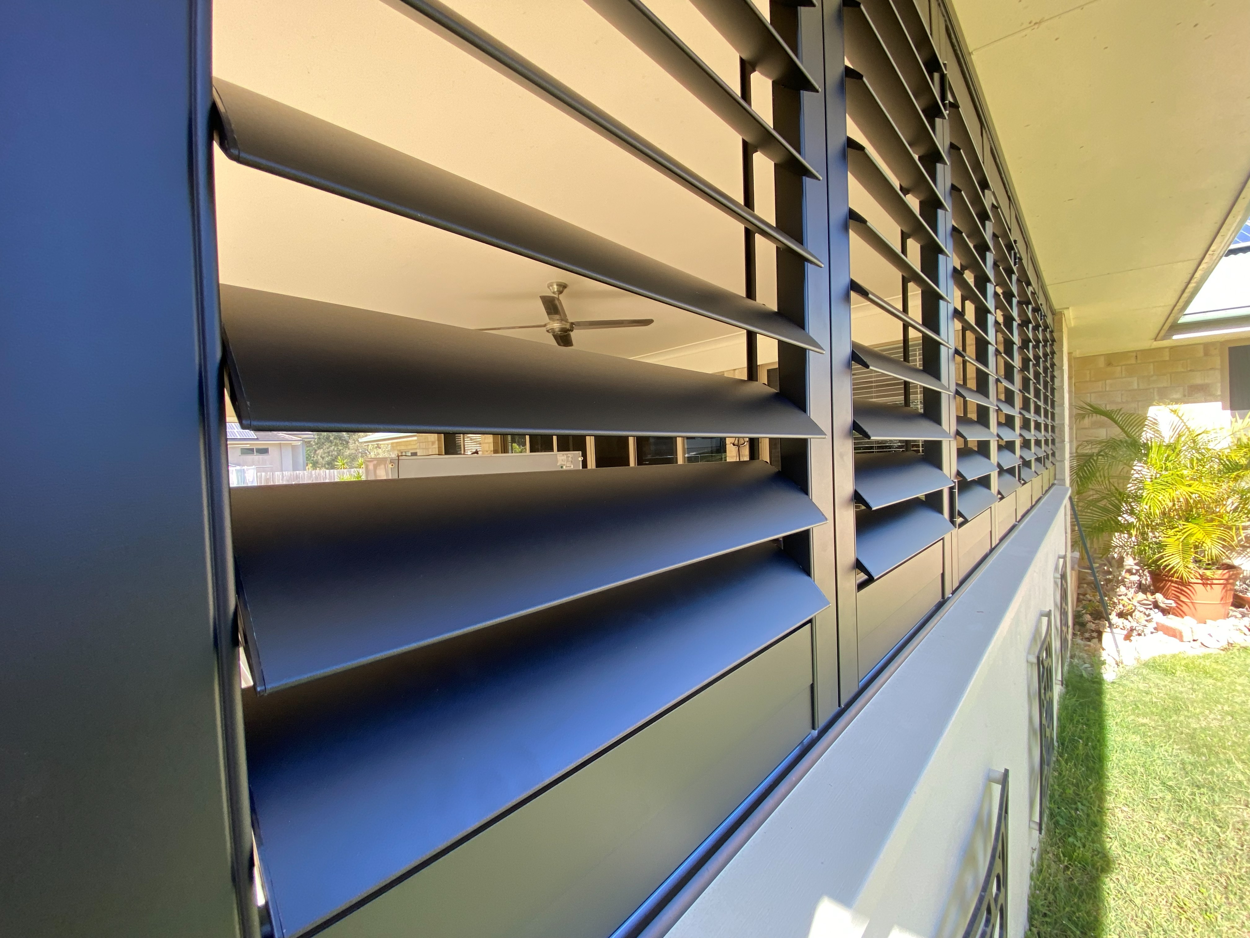 Close-up of black aluminium shutter louvre blades on a covered patio