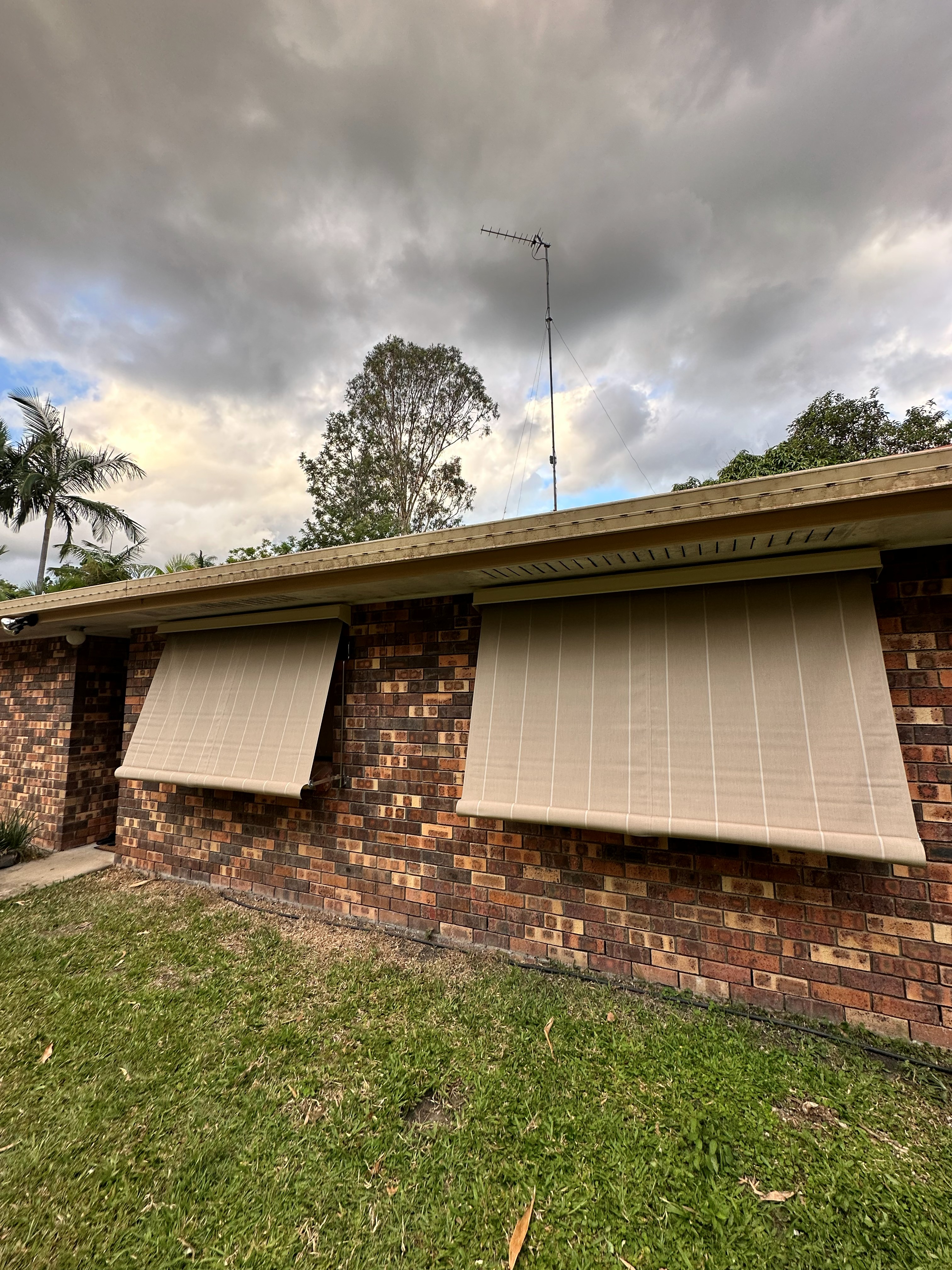 Dark grey auto guide awnings on a two-storey home with garage doors