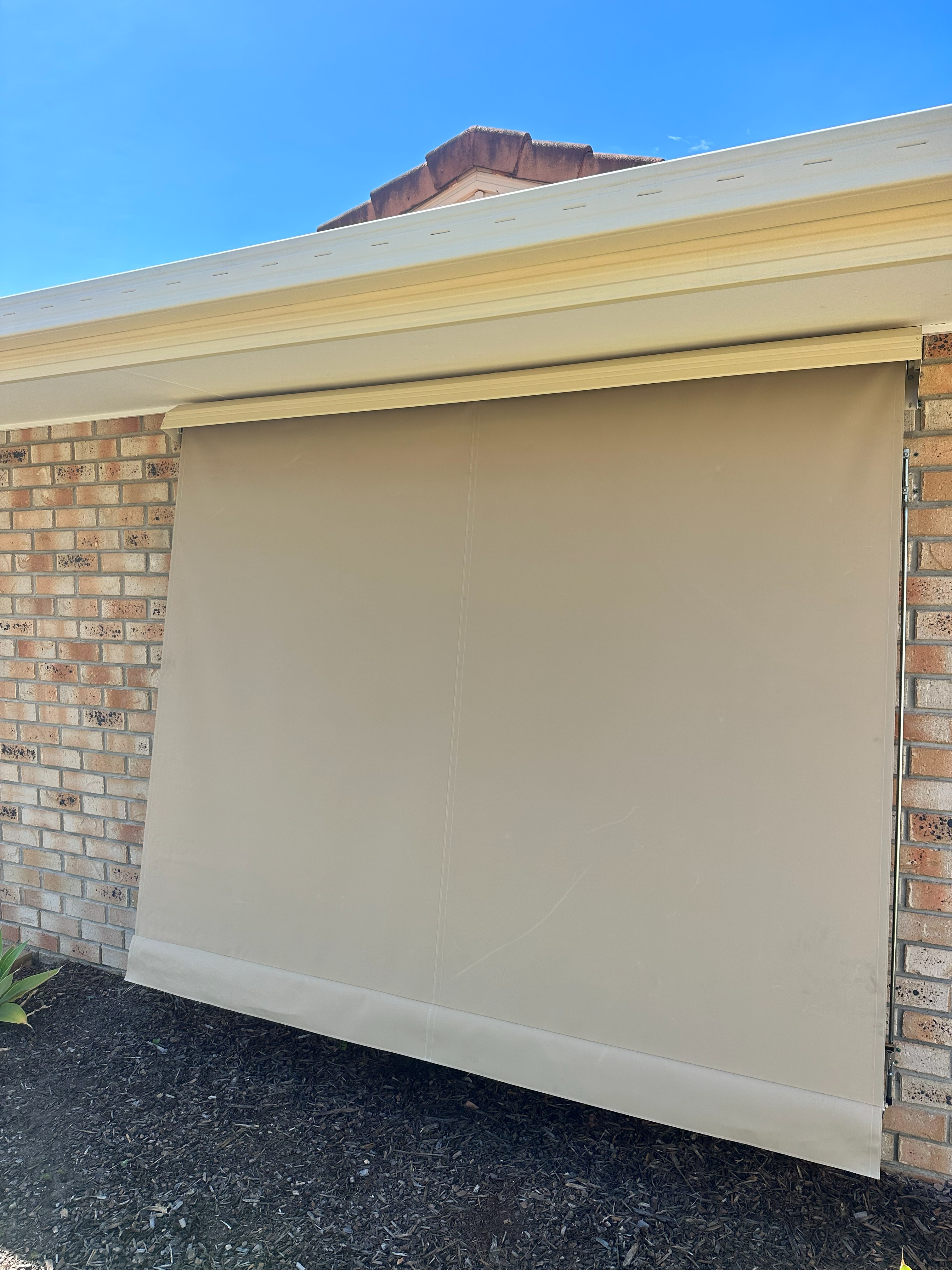 Beige auto guide awning fully lowered over a garage-style opening