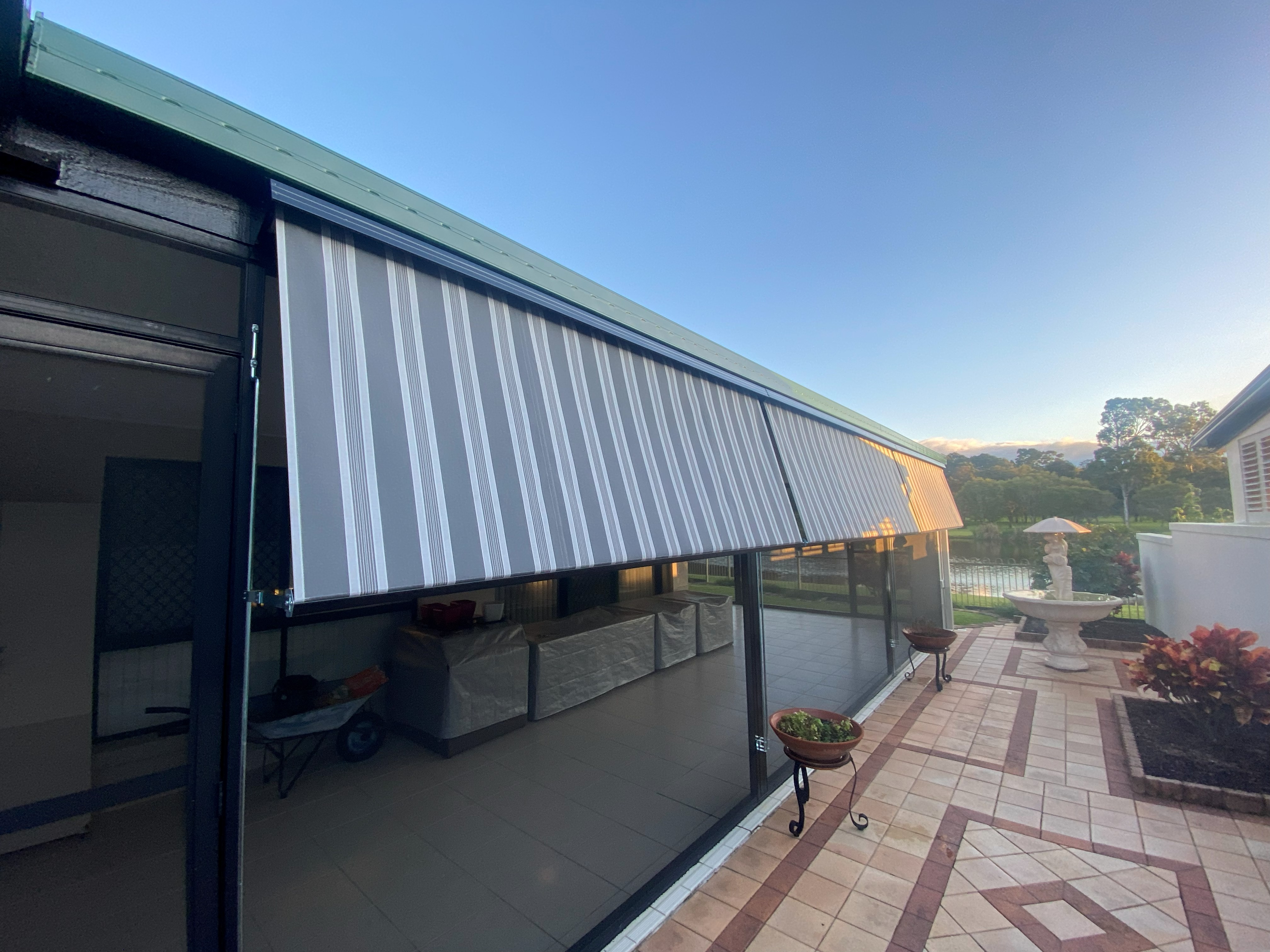 Striped auto guide awning extended over an alfresco entertaining area
