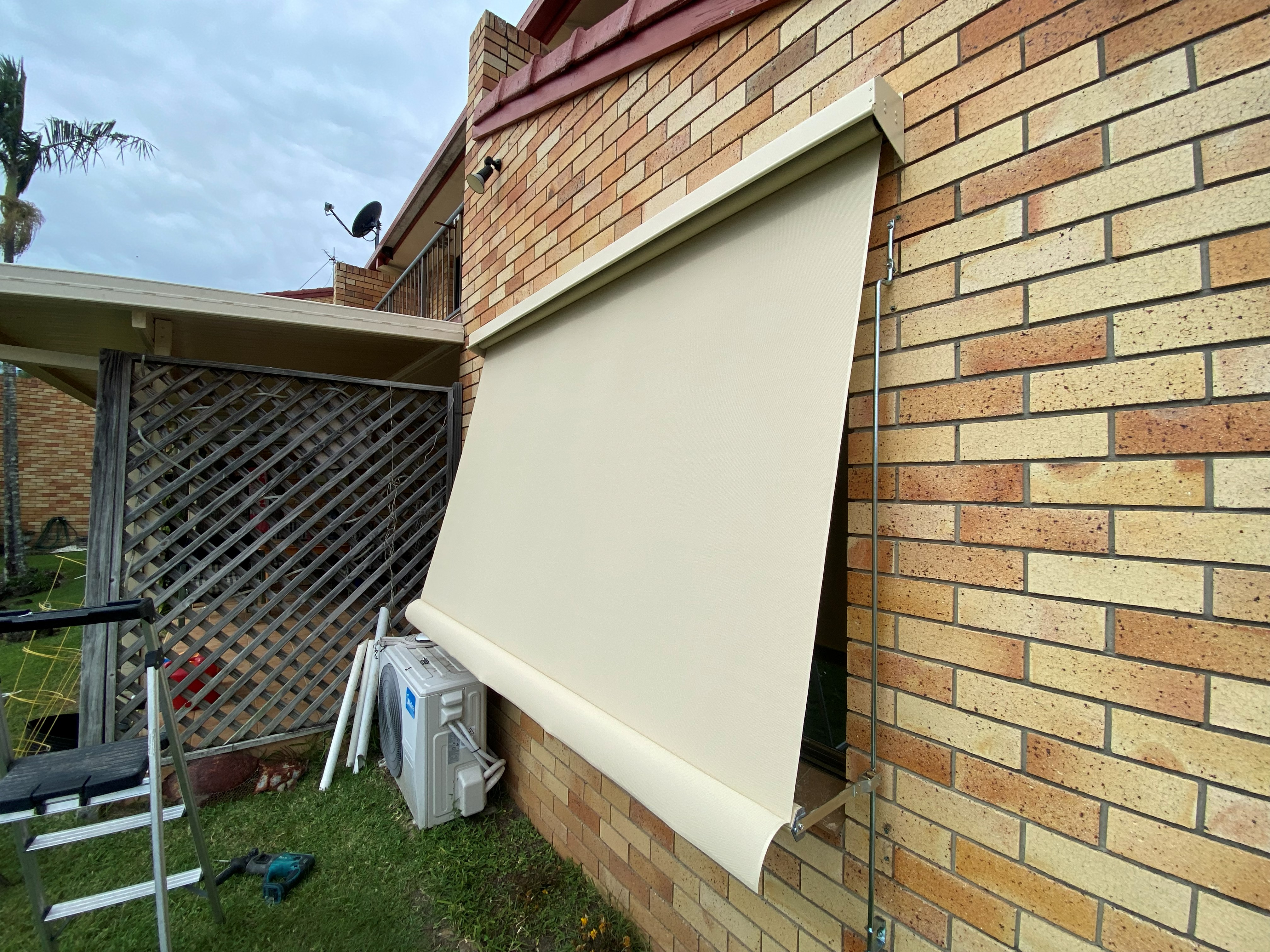 Beige auto guide awning lowered over a brick home window