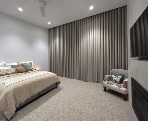 Taupe block out curtains fitted along a bedroom wall beside the bed