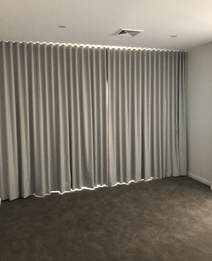 Grey block out curtains fitted along a living room wall