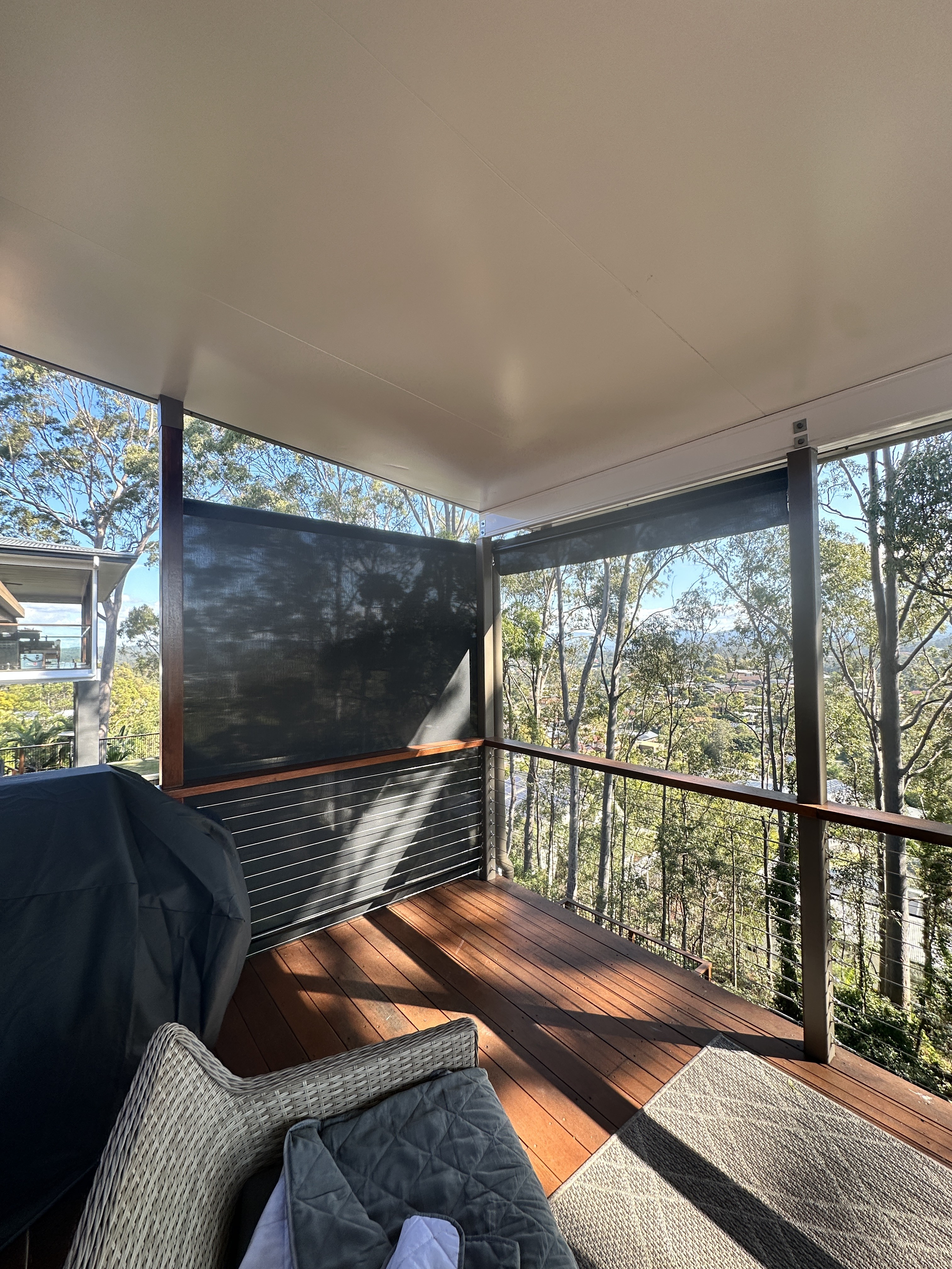Crank operated outdoor blind fitted to a timber deck corner with treetop views