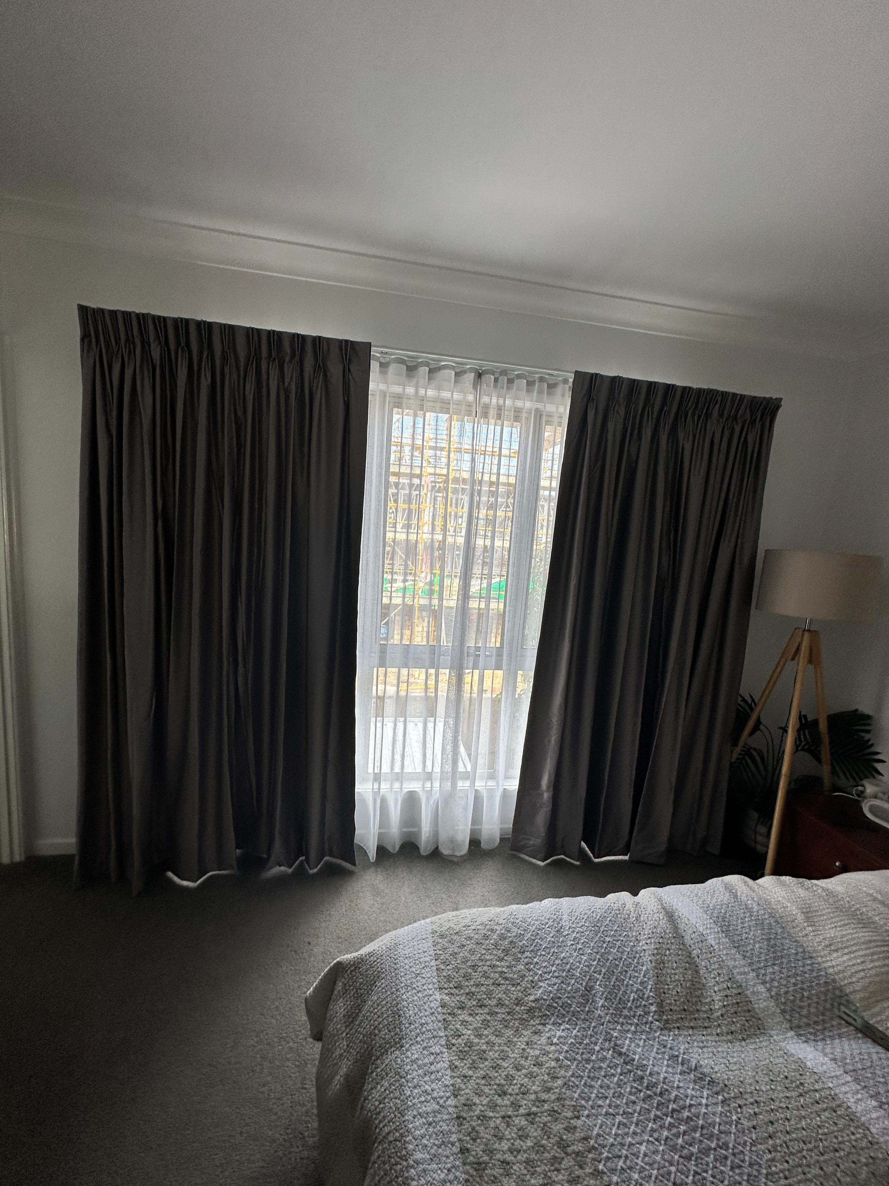 Double track curtains with sheer and blockout layers in a bedroom overlooking a construction site