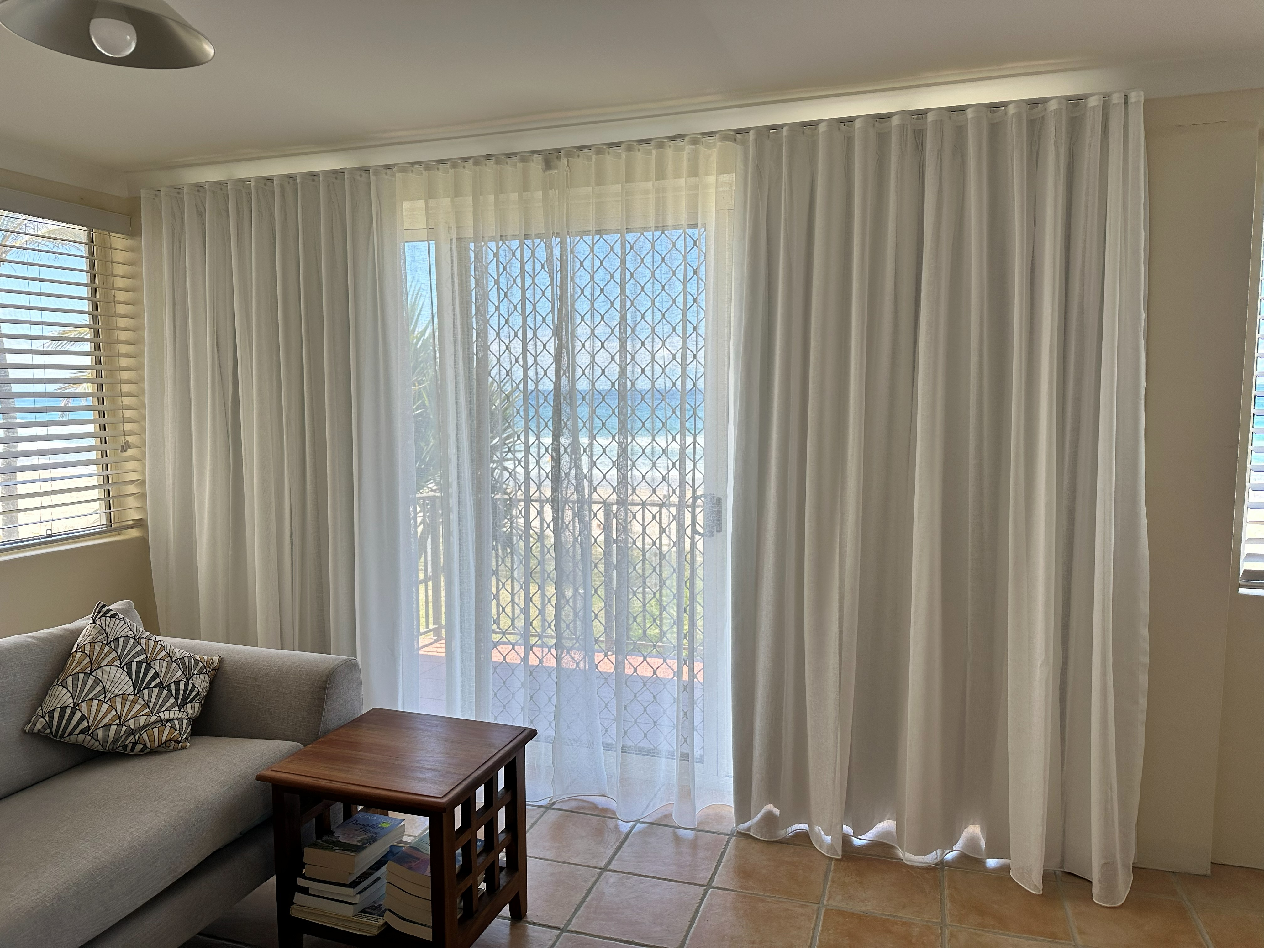 Double track curtains with sheer and blockout layers in a beachfront living room