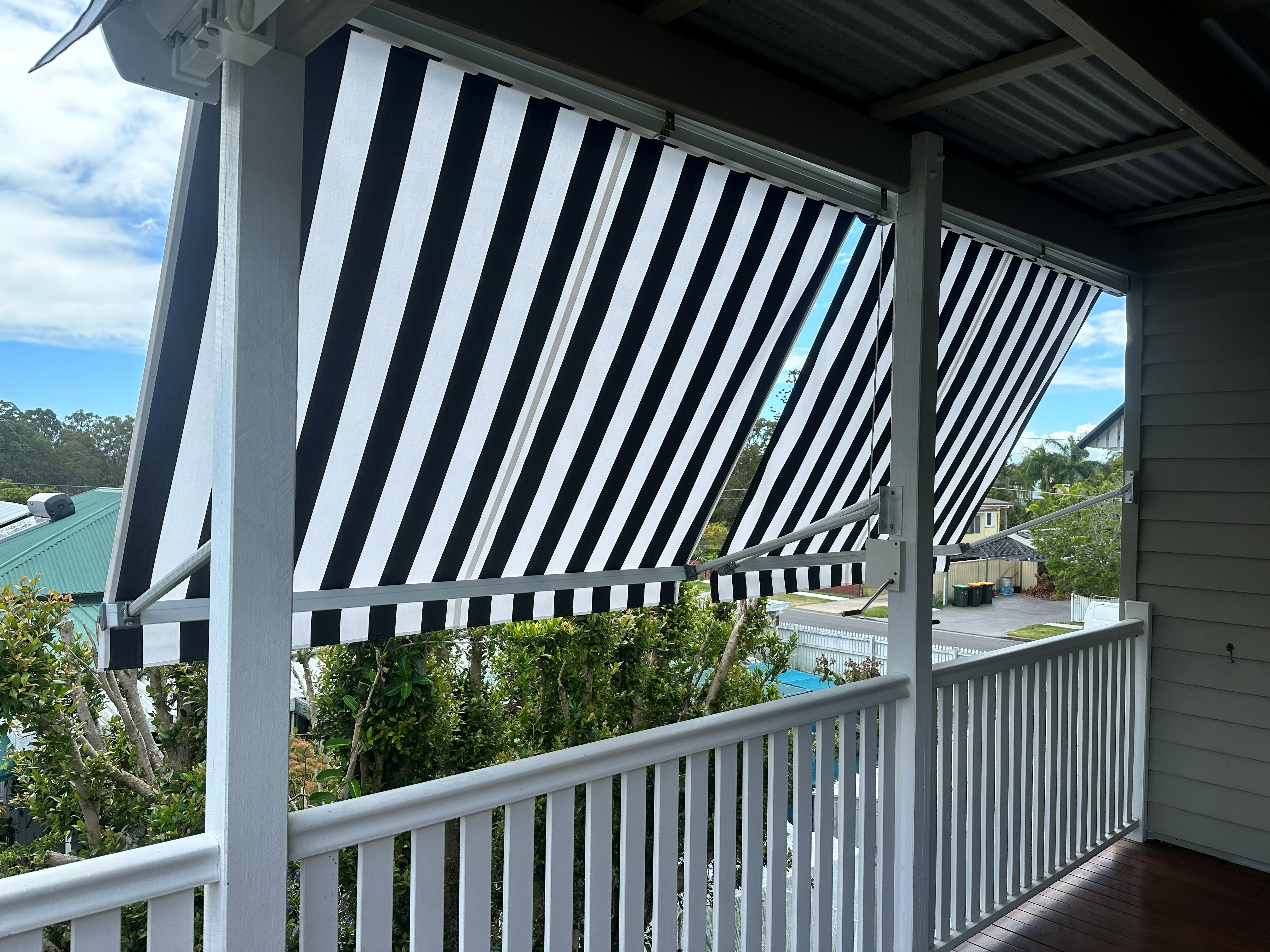 Striped drop arm awning extended over a balcony