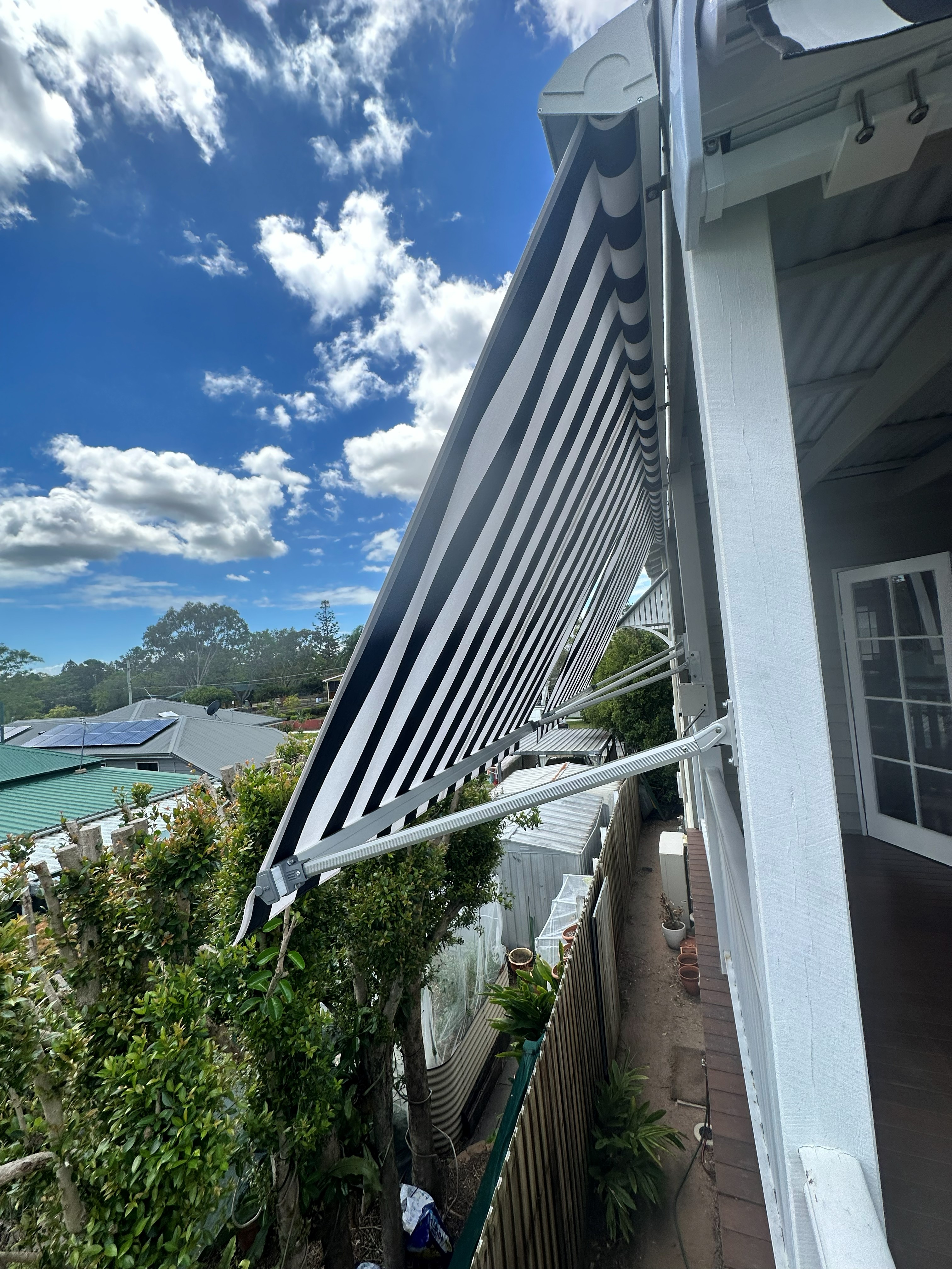 Striped drop arm awning extended on a sunny balcony
