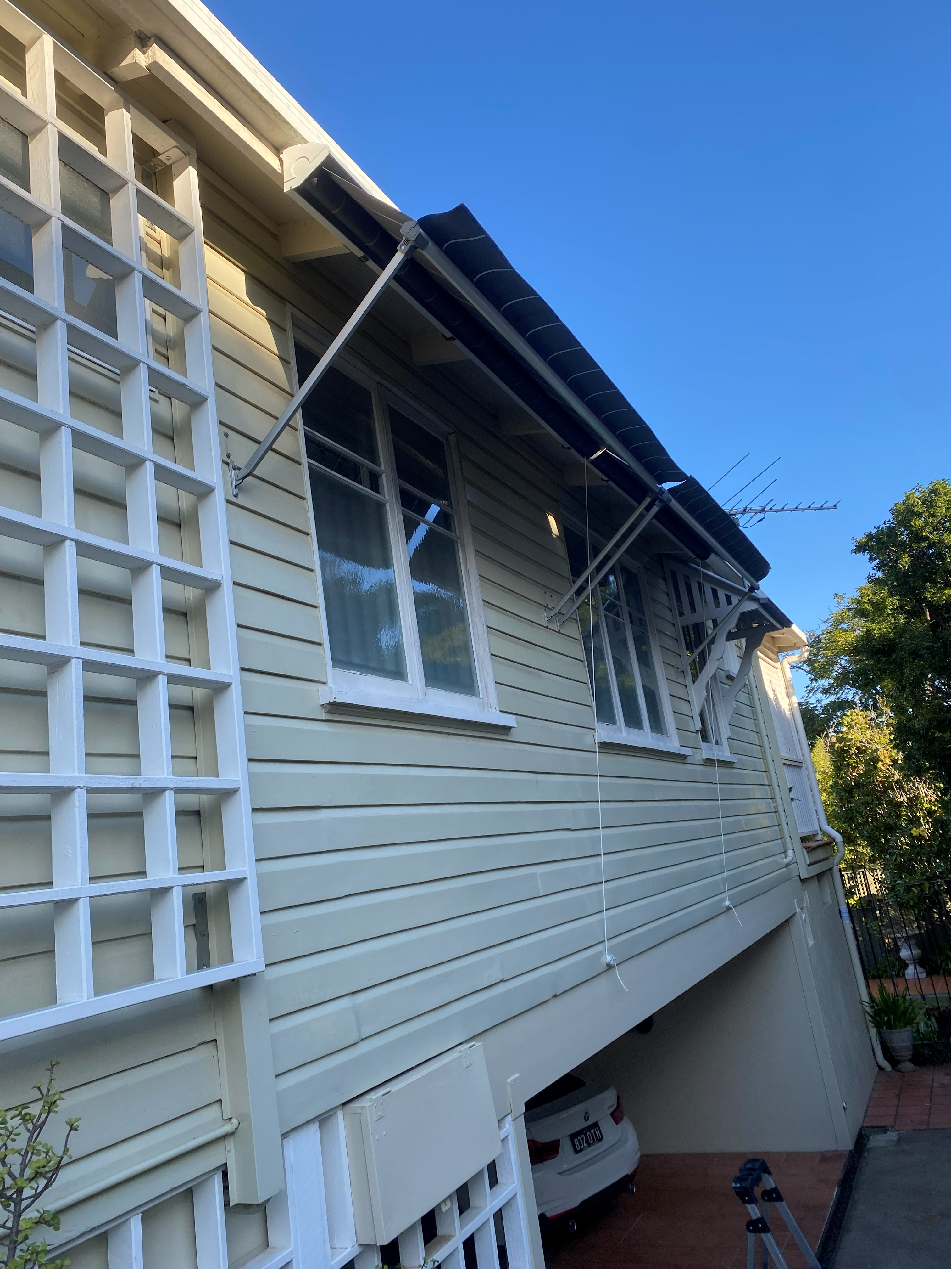 Navy drop arm awnings extended over weatherboard home windows