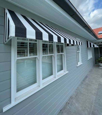 Striped fixed canopy fabric awning fitted over multiple windows