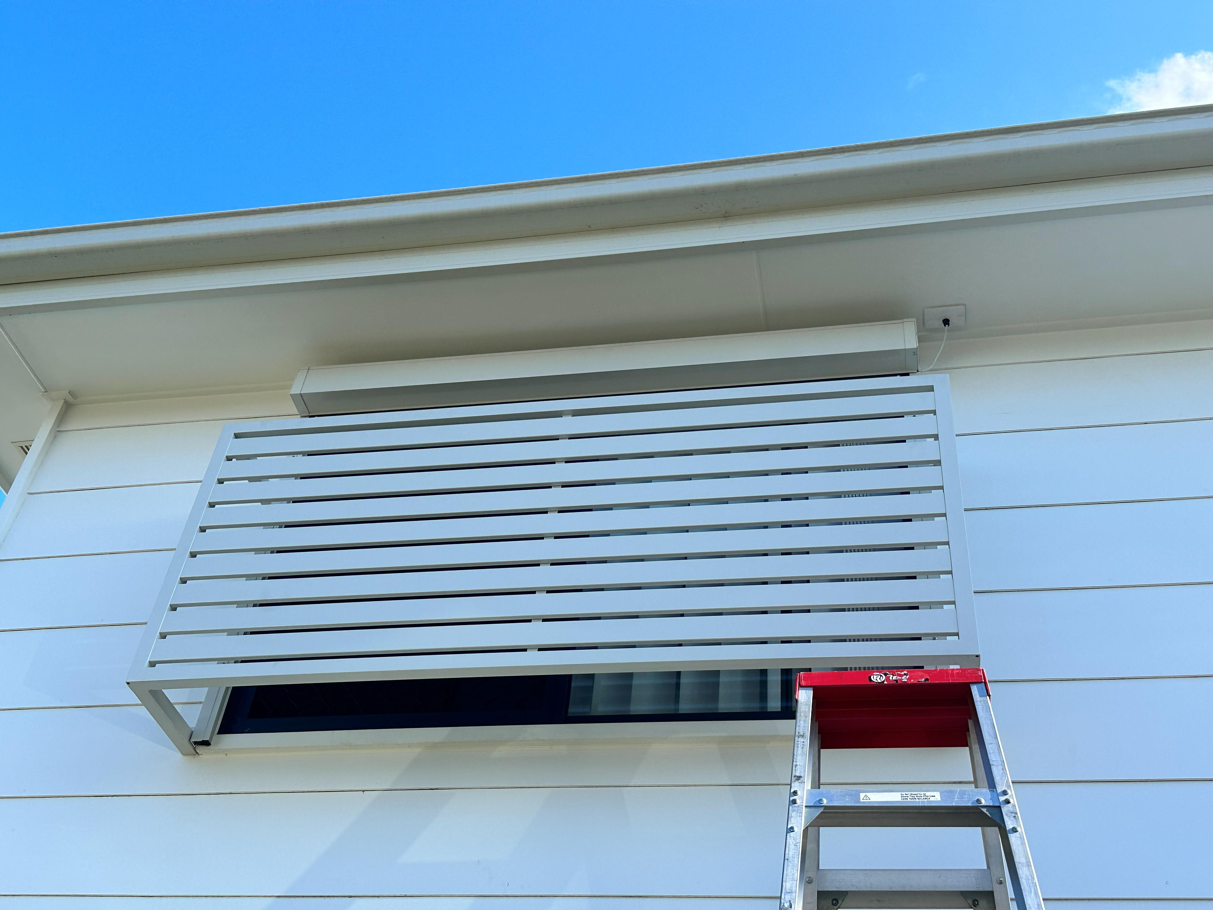 White flat fixed privacy screen fitted above a window on a rendered home