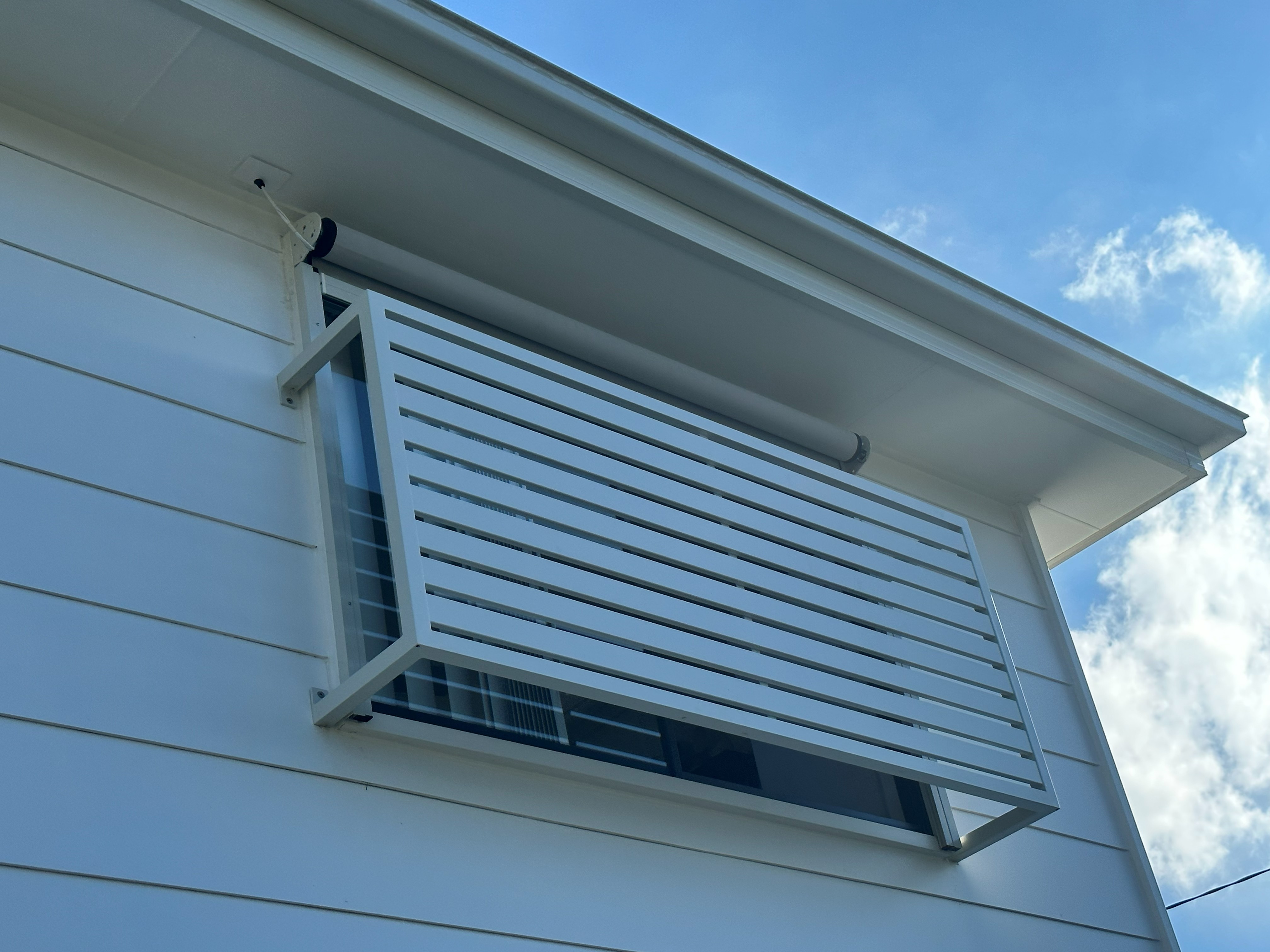 White flat fixed privacy screen fitted to a window beside a roller shutter