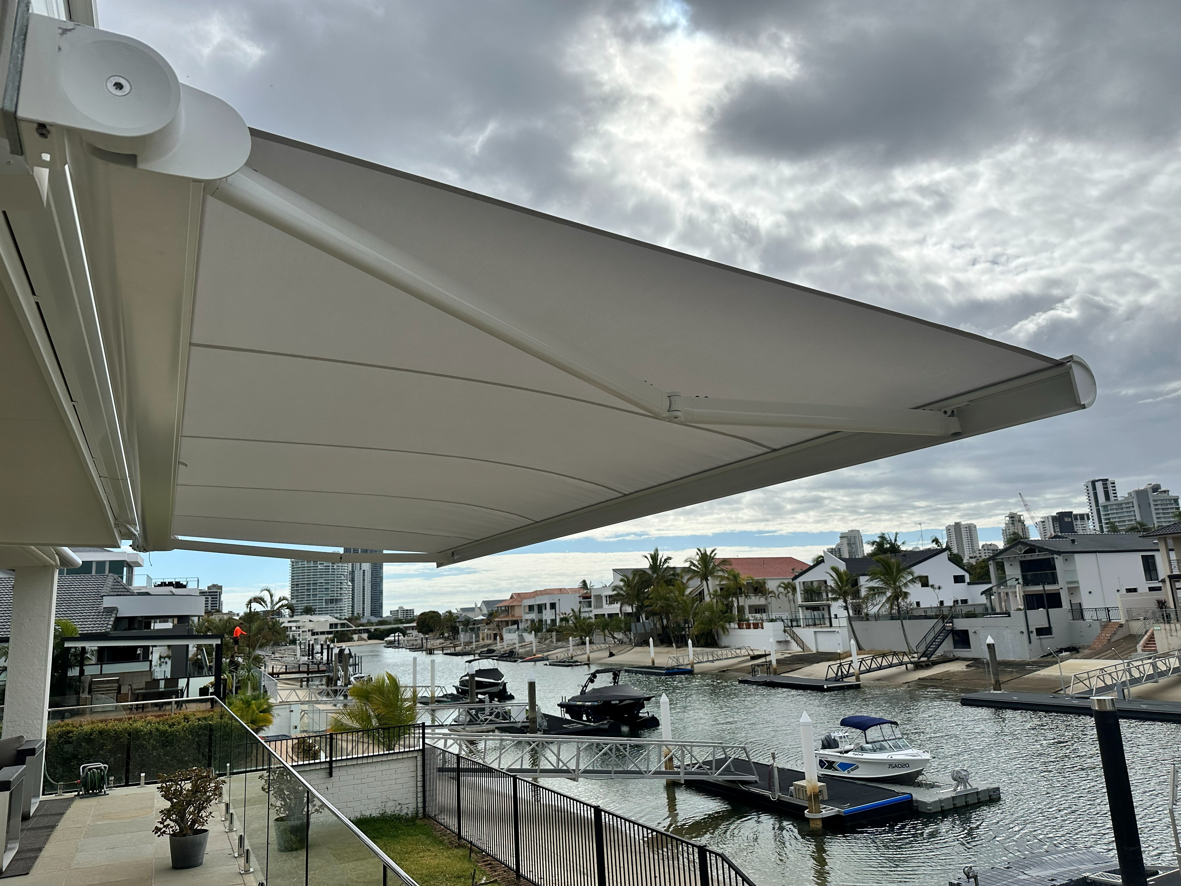 Folding arm awning extended over a waterfront balcony overlooking a marina