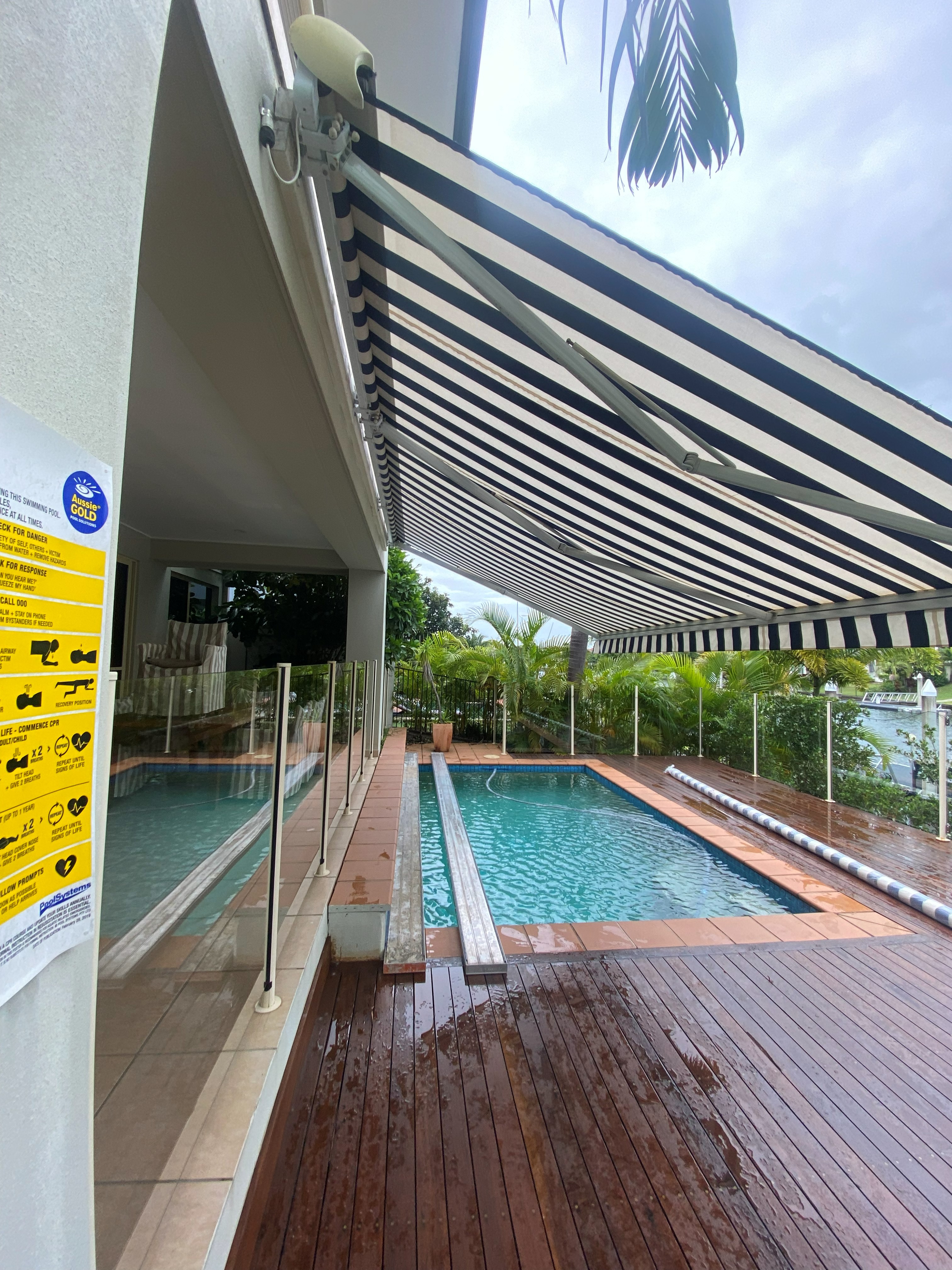 Navy striped folding arm awning extended over a pool deck