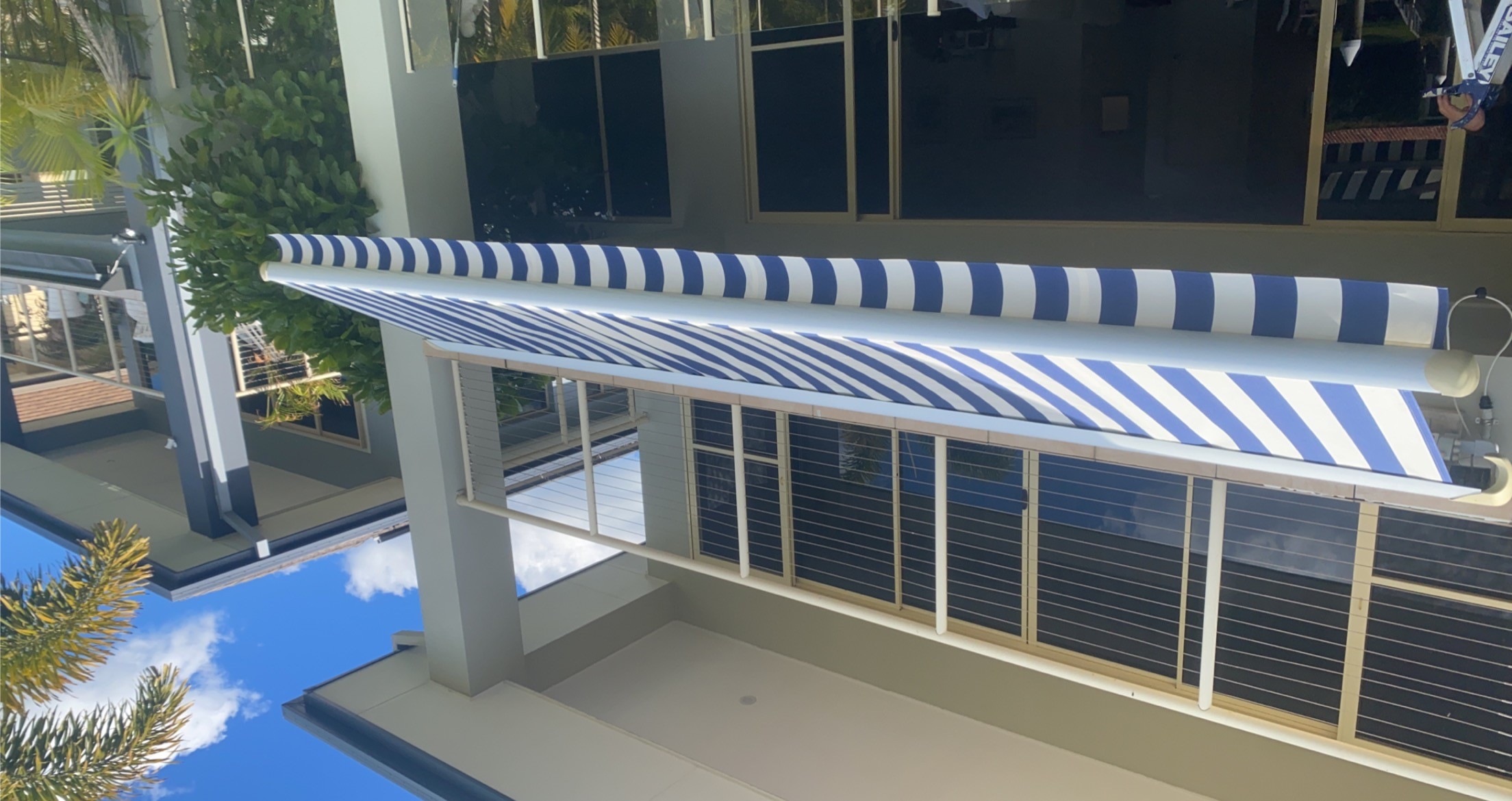 Blue striped folding arm awning extended over a high-rise balcony