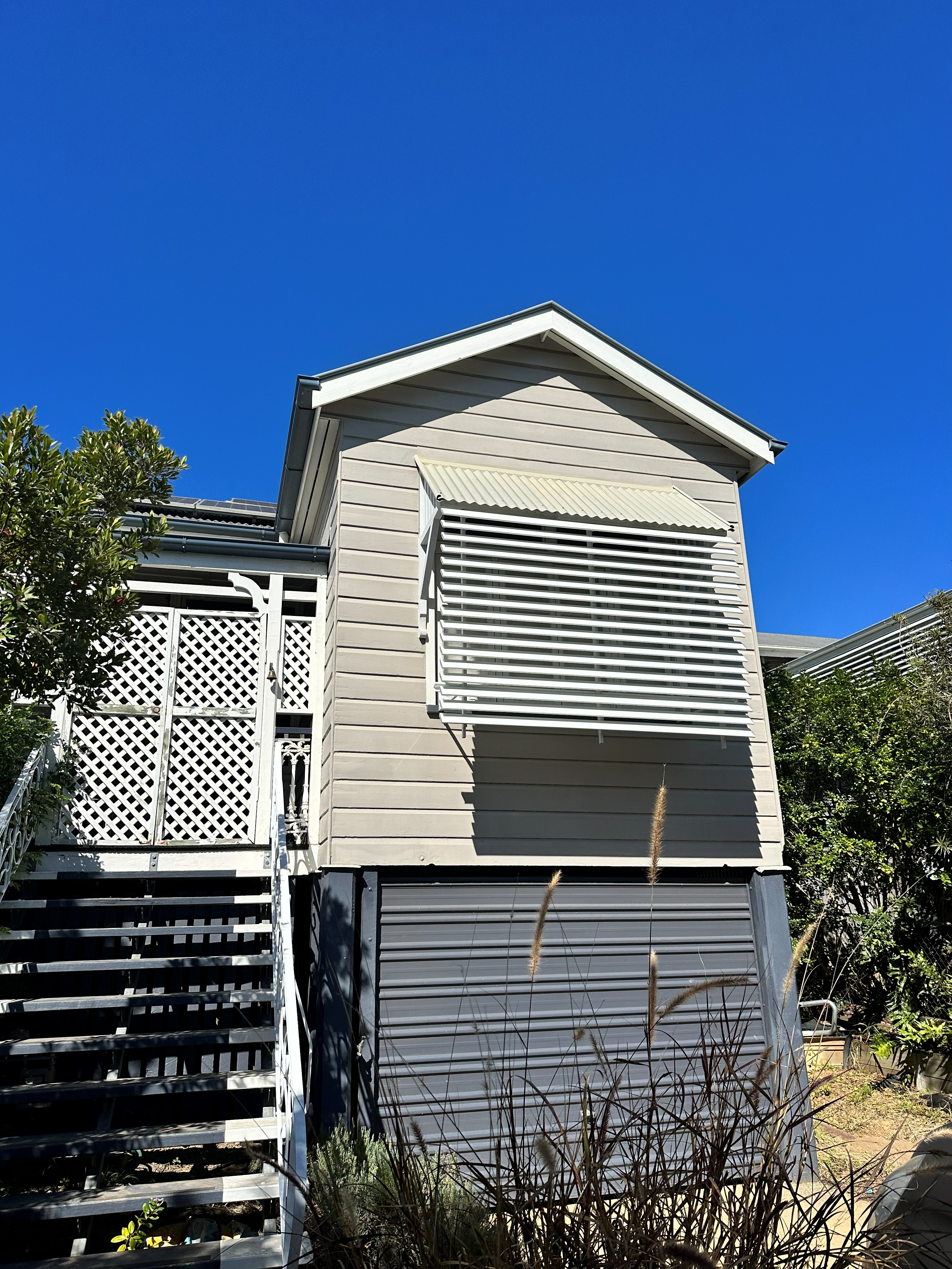 White louvre awning fitted over a weatherboard home window
