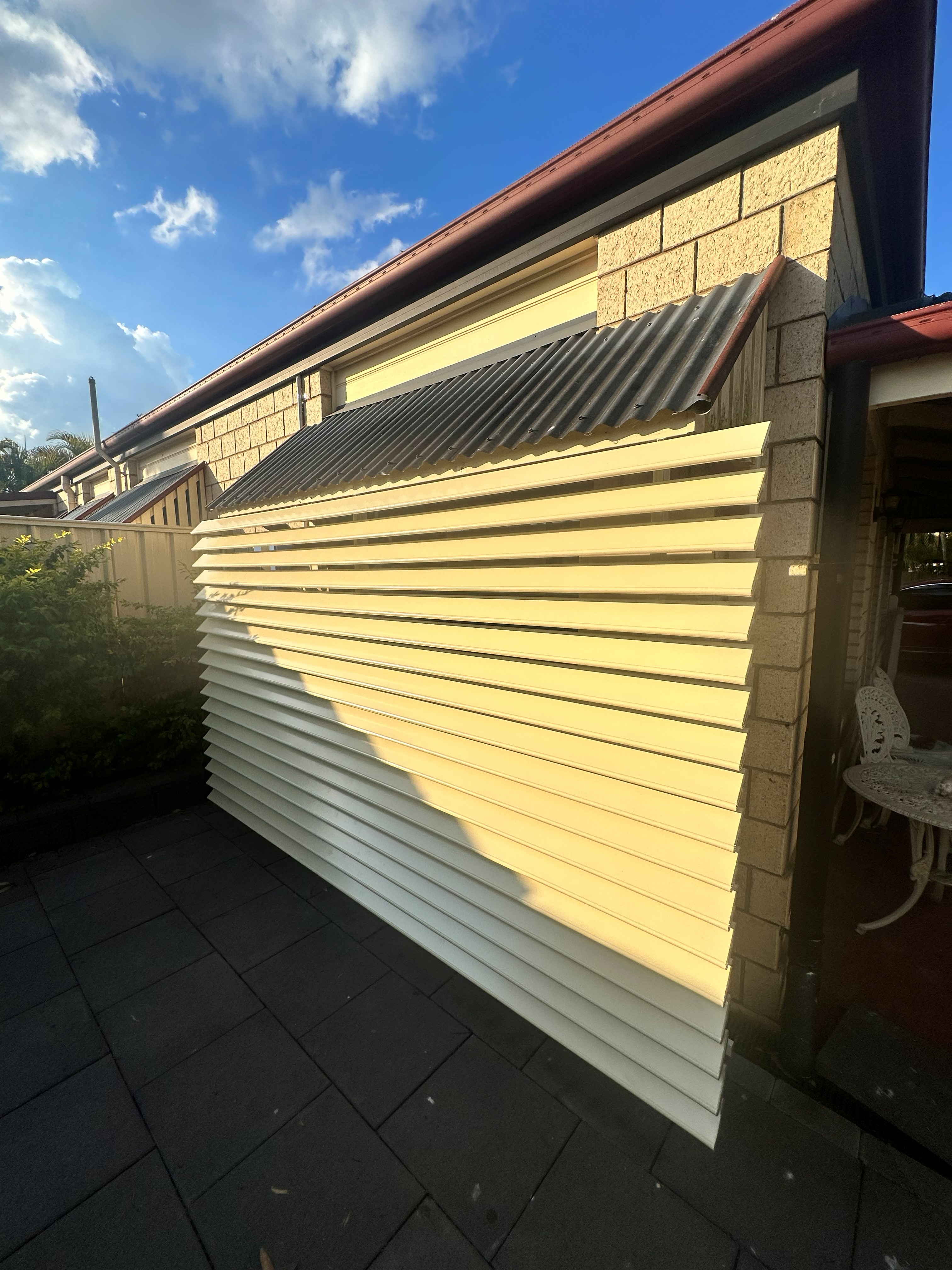 Cream louvre awning fitted over a brick home window