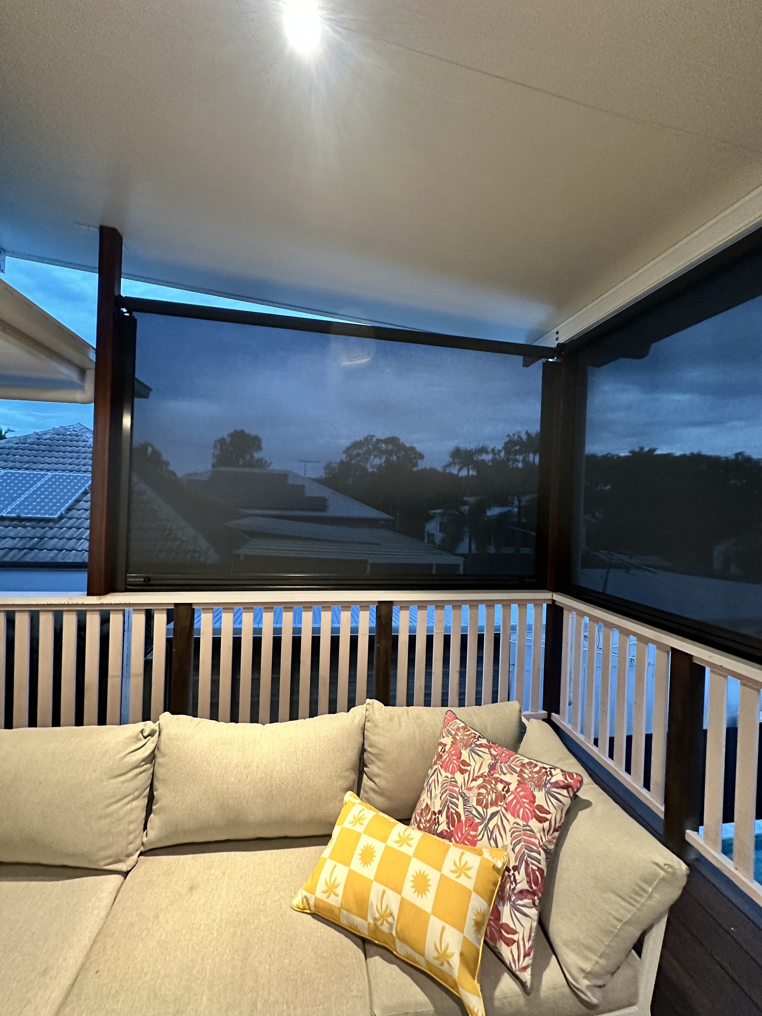 Multi-Stop Channel outdoor blind lowered on a corner balcony above a lounge seating area