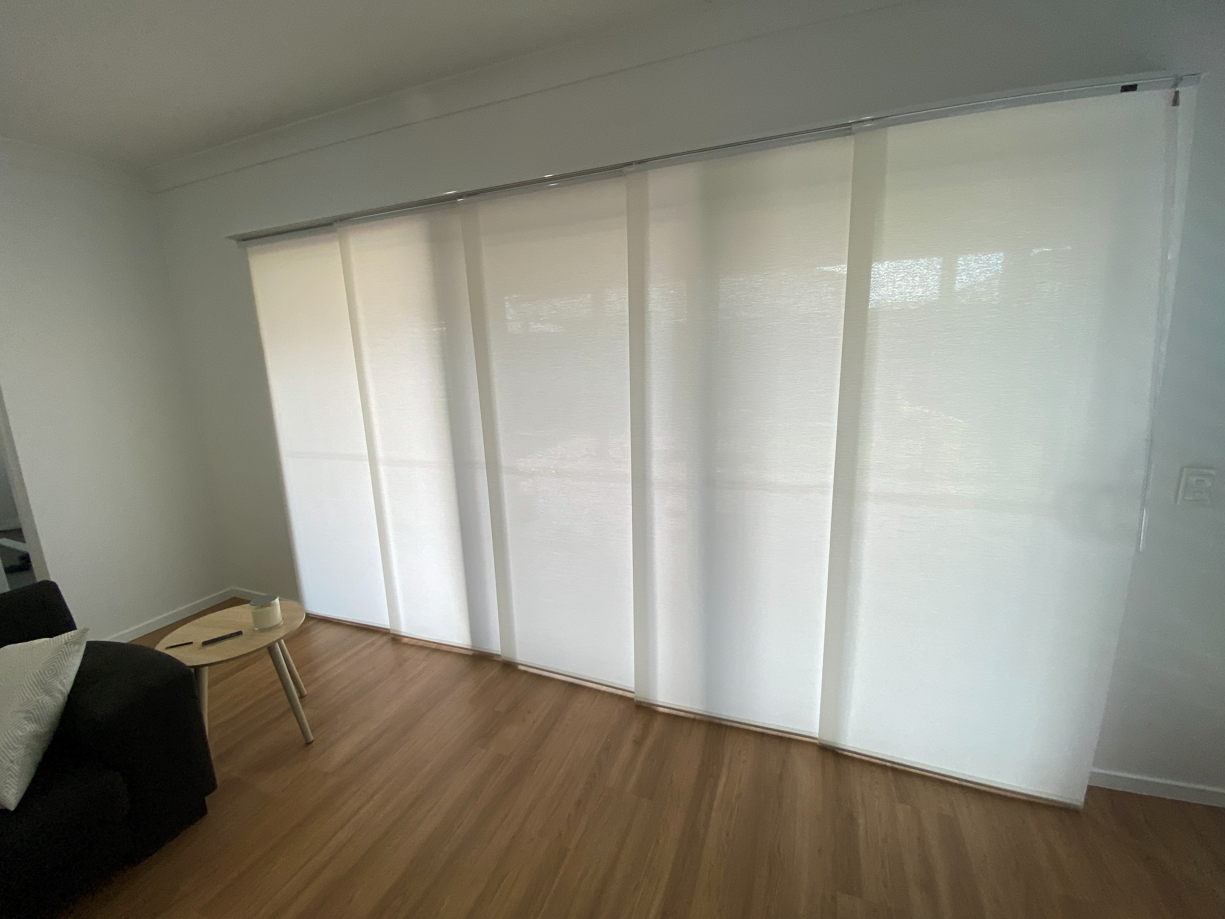 White panel glide blinds fitted to a wide living room sliding door