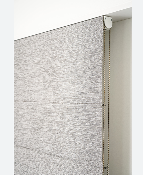 Close-up of a grey roman blind fabric and chain mechanism
