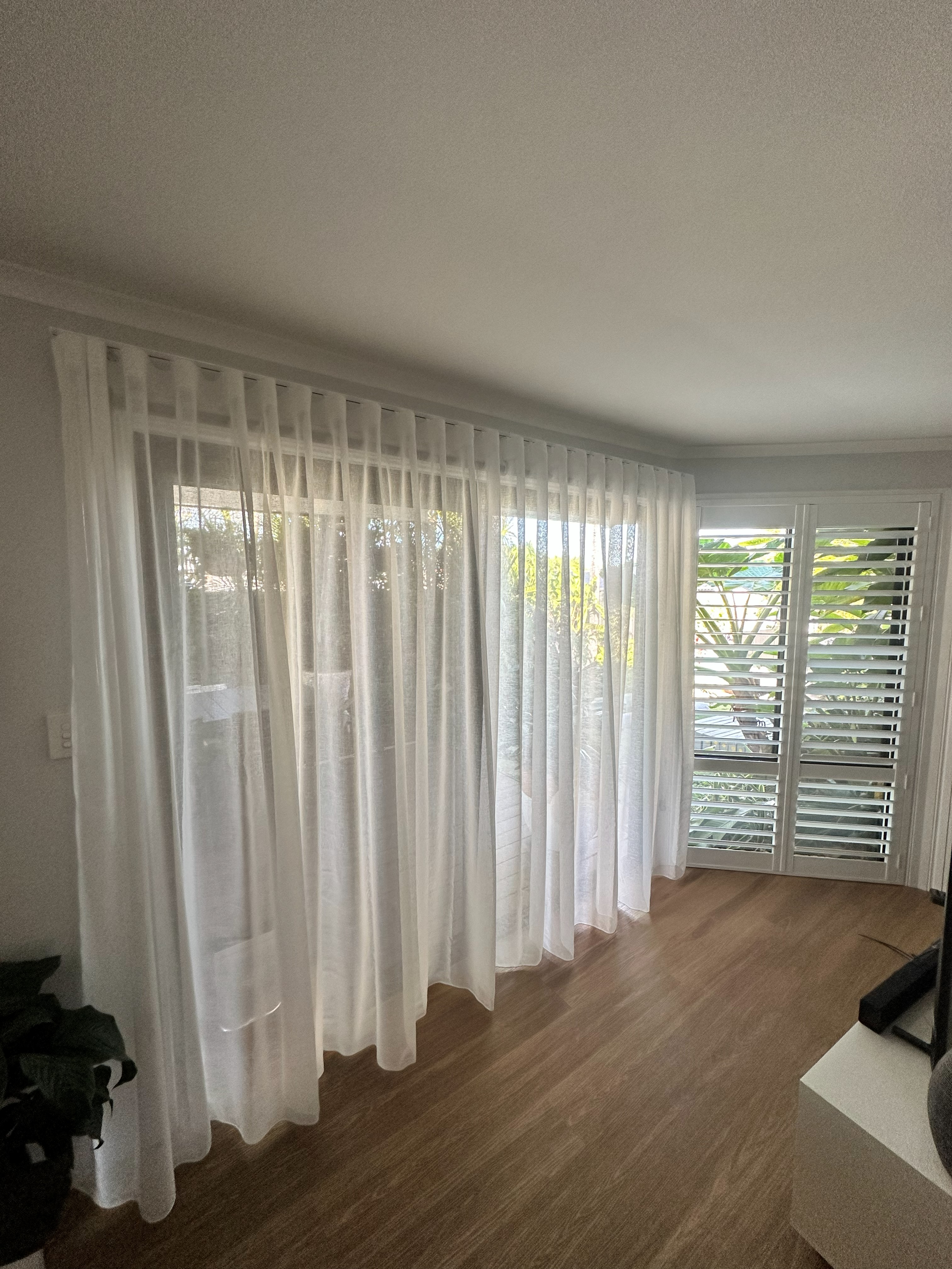 Sheer curtains along a living room wall of sliding doors with garden view