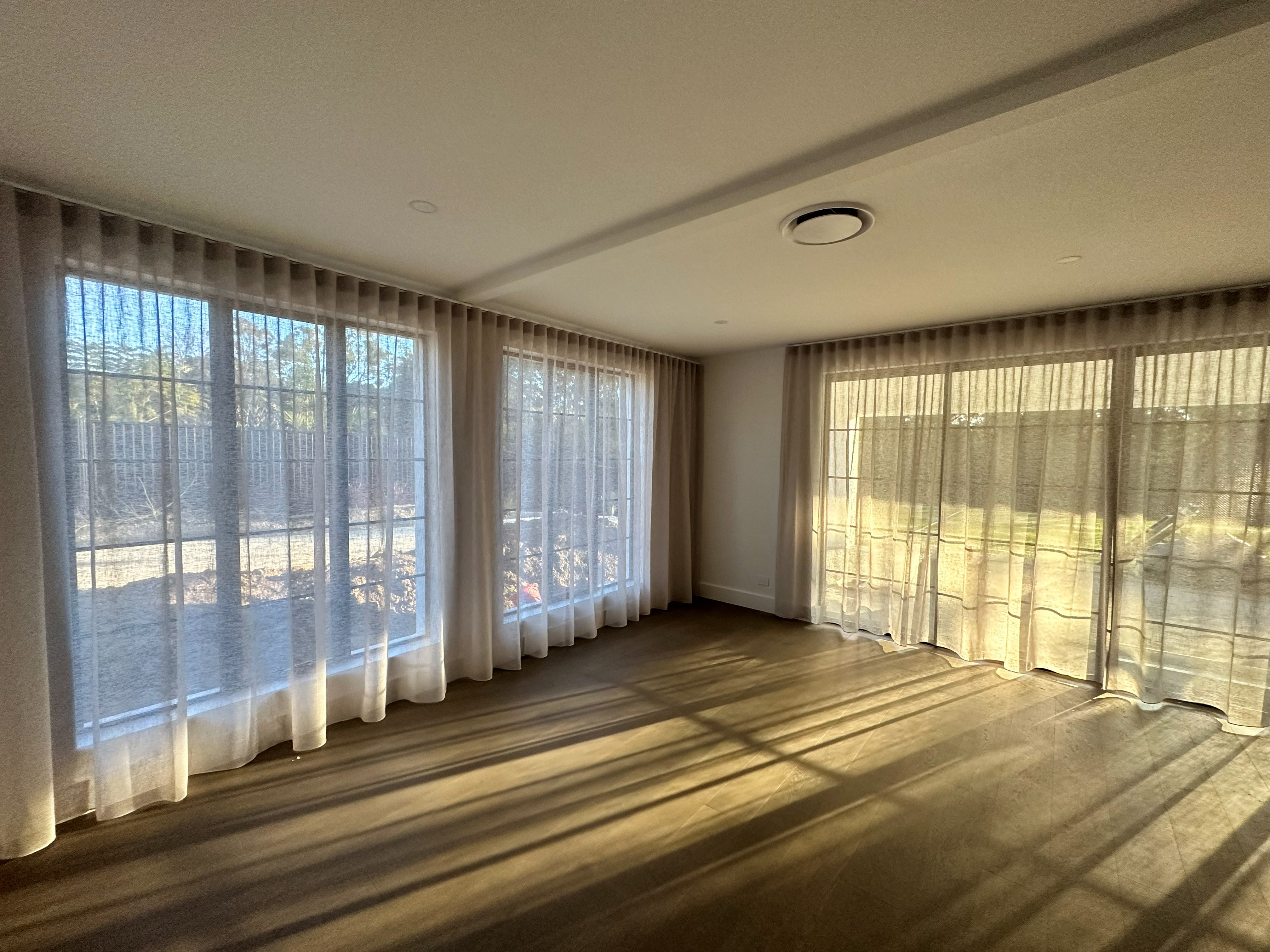 Sheer curtains along a corner living area with kitchen and dining views