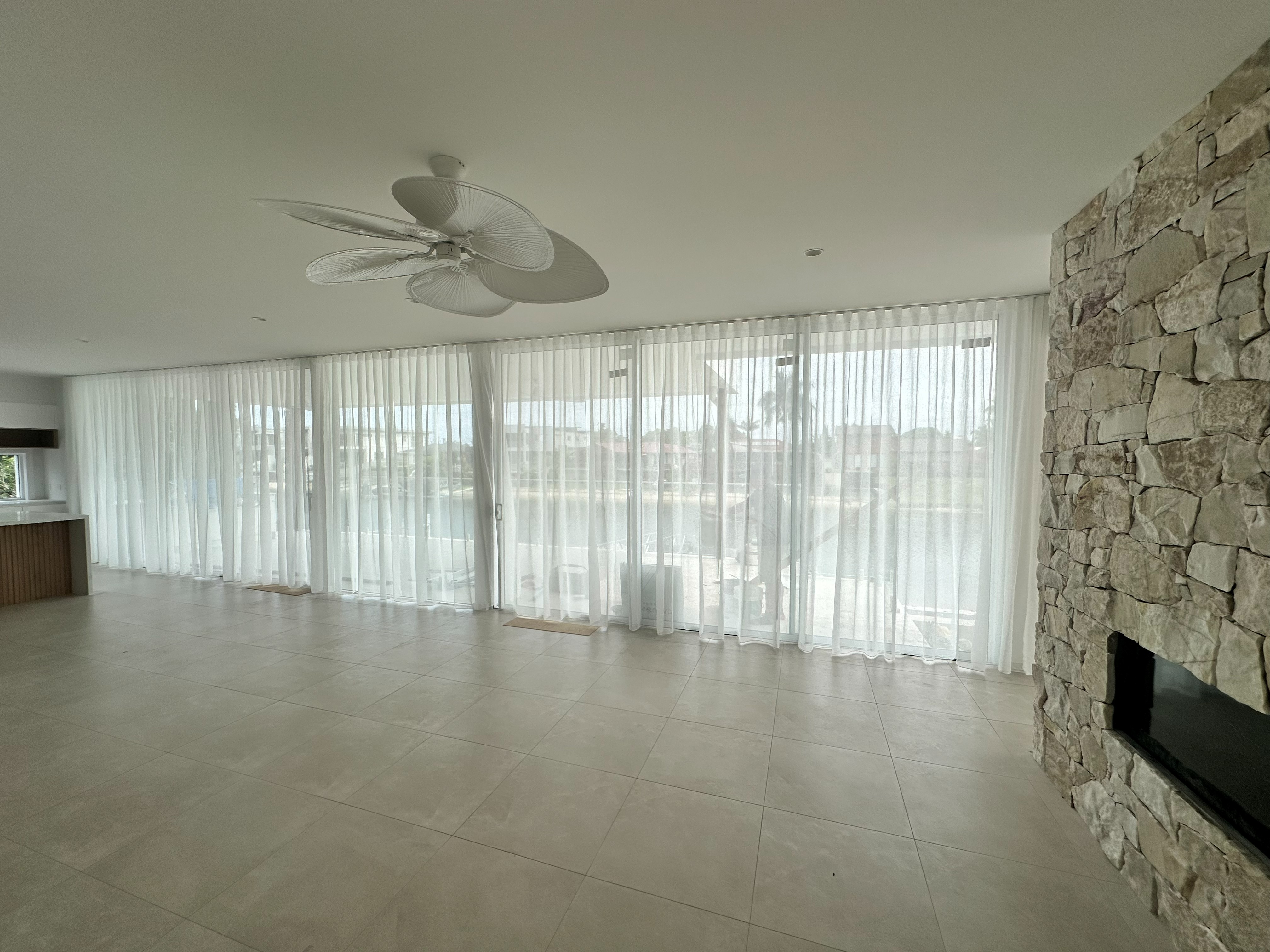 Sheer curtains along a living room overlooking a canal beside a stone fireplace