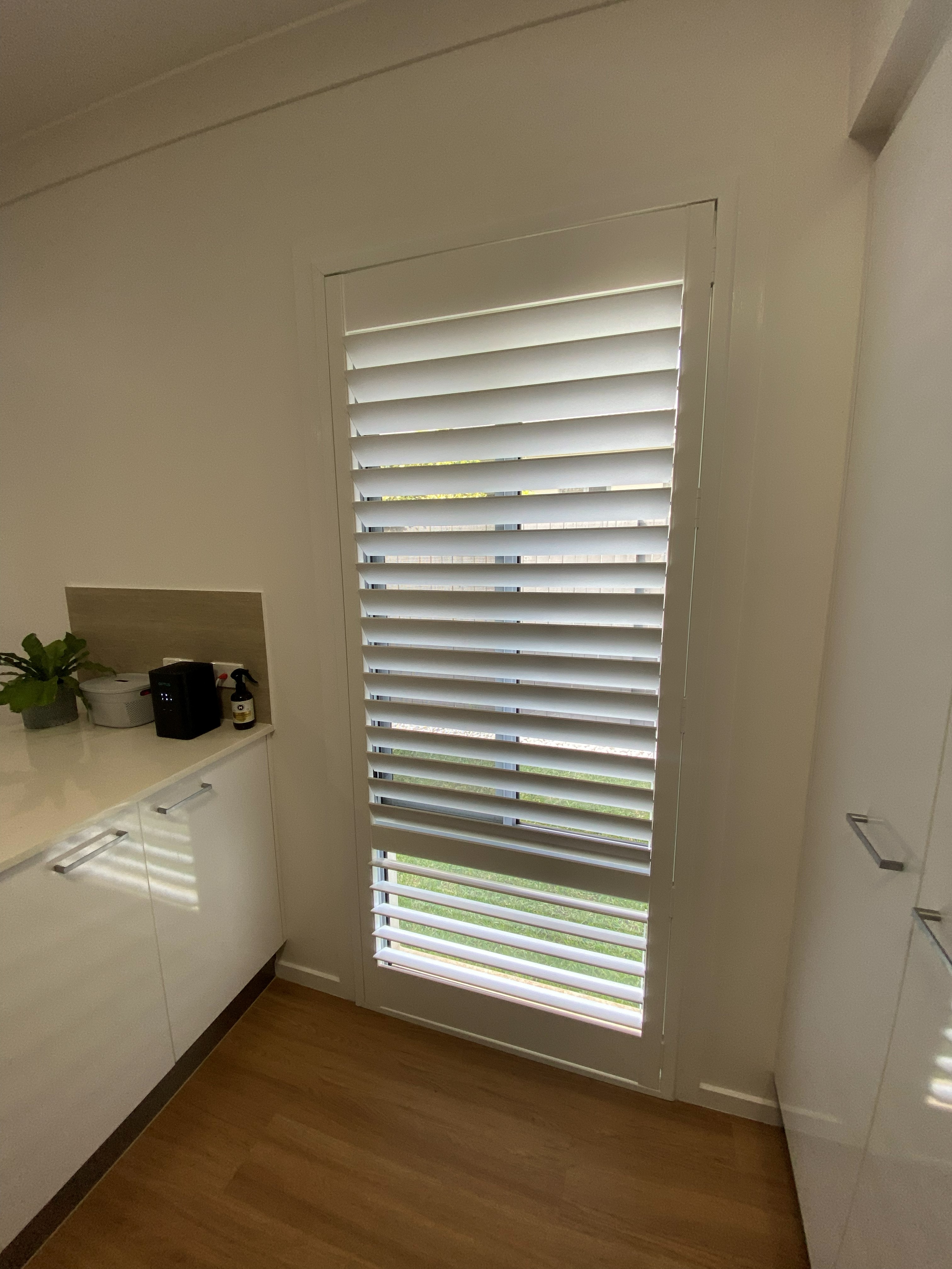 Plantation shutters in a dressing room walkway beside a mirrored wardrobe