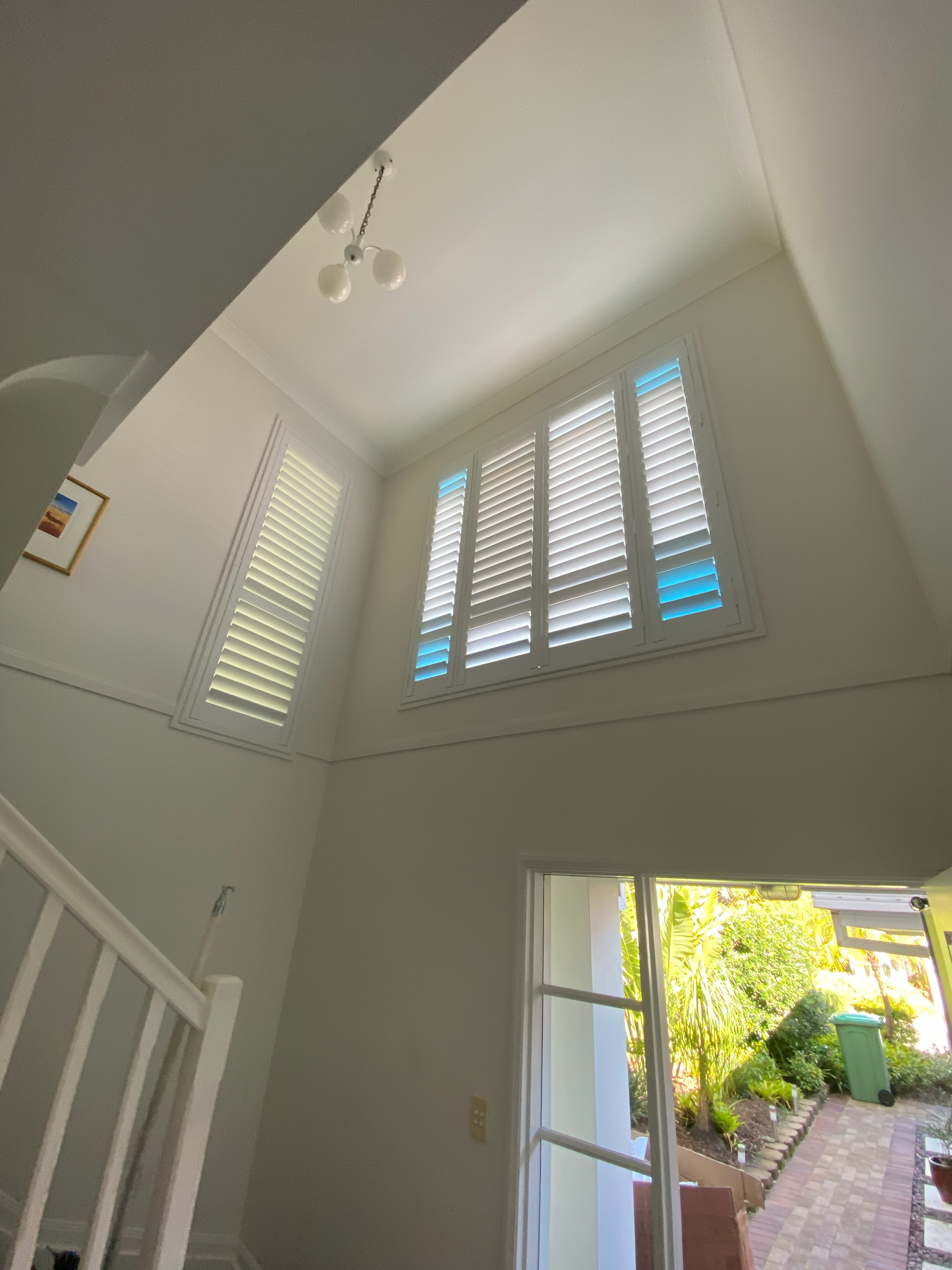 Corner plantation shutters in a high vaulted entry beside a staircase
