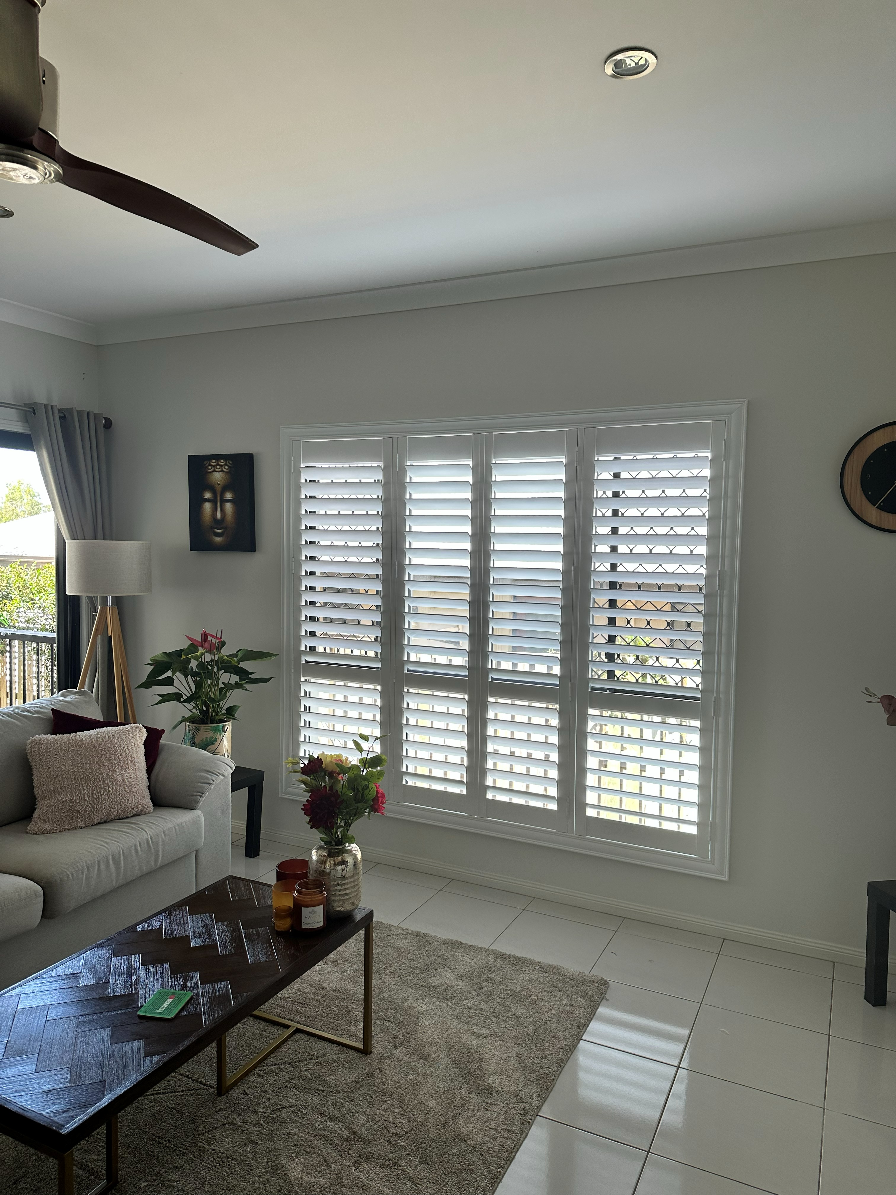 Plantation shutters in a living room with a wall-mounted TV and floor lamp