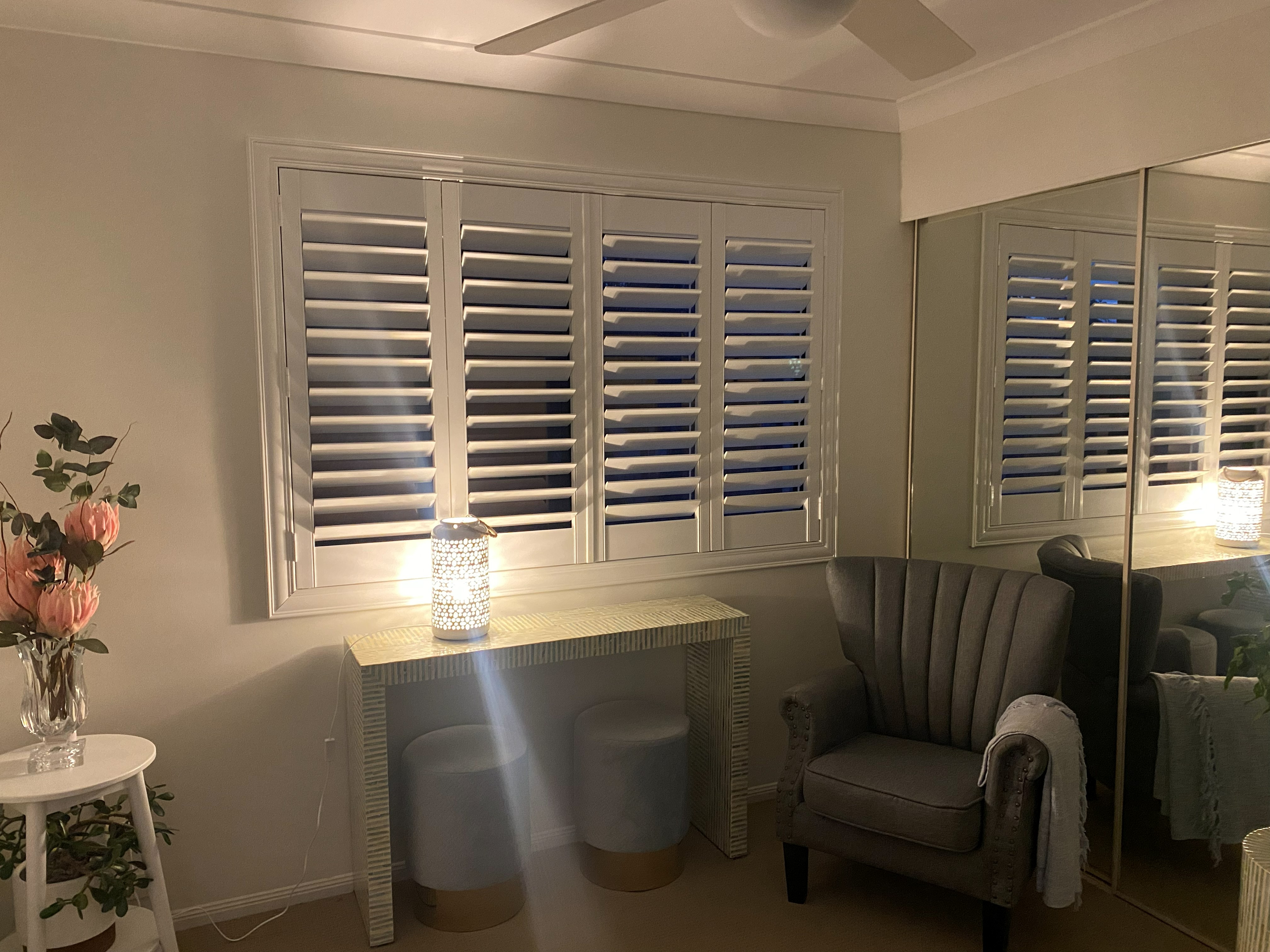 Plantation shutters on twin bedroom windows either side of a wall-mounted TV