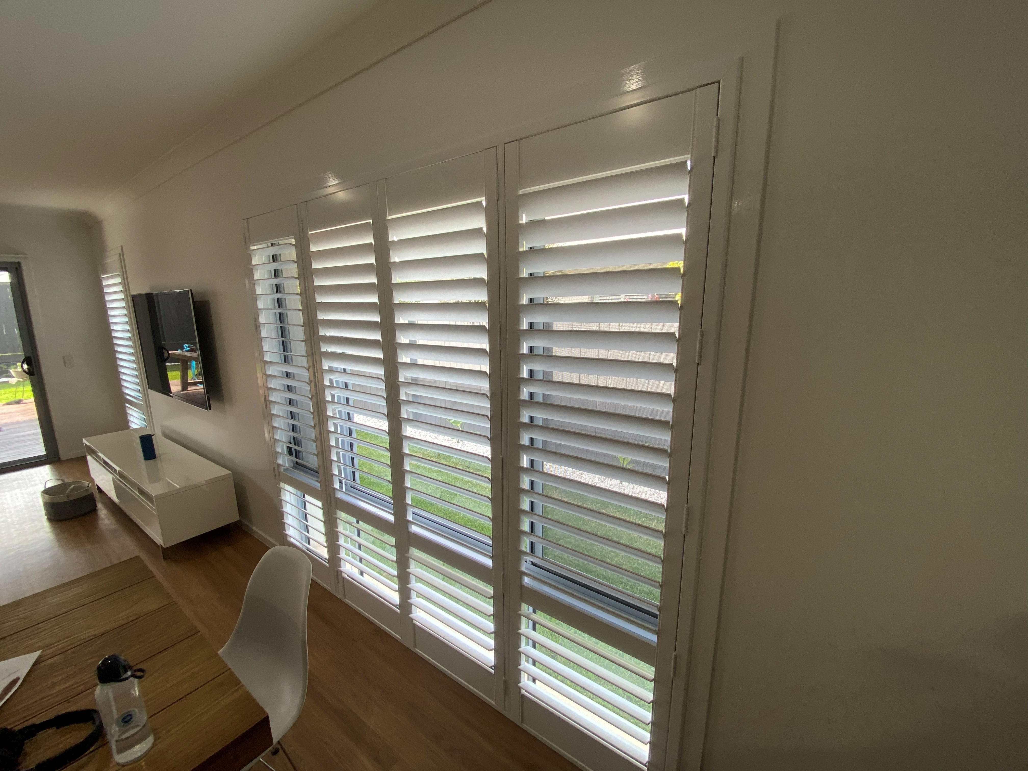 Tall plantation shutter above a kitchen bench with a potted plant