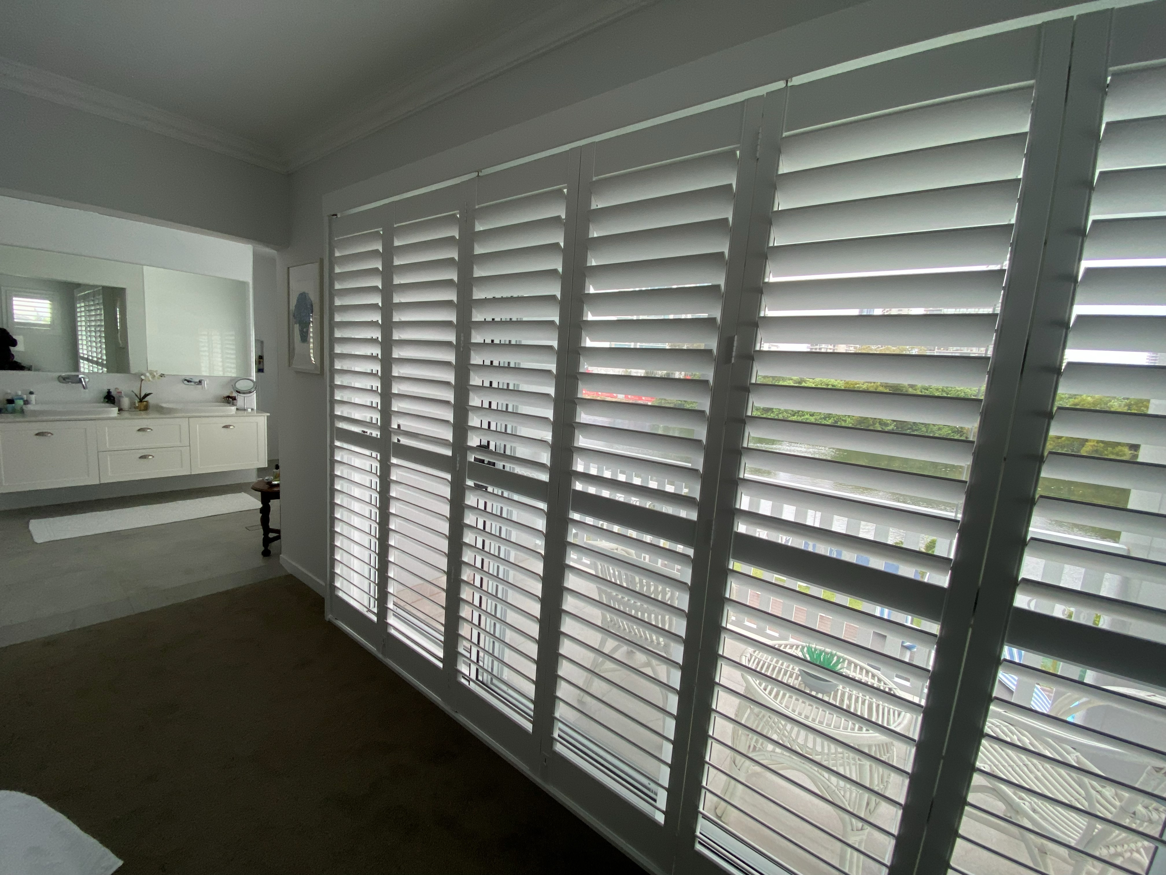 Sliding shutters in a bedroom overlooking a river and city apartments