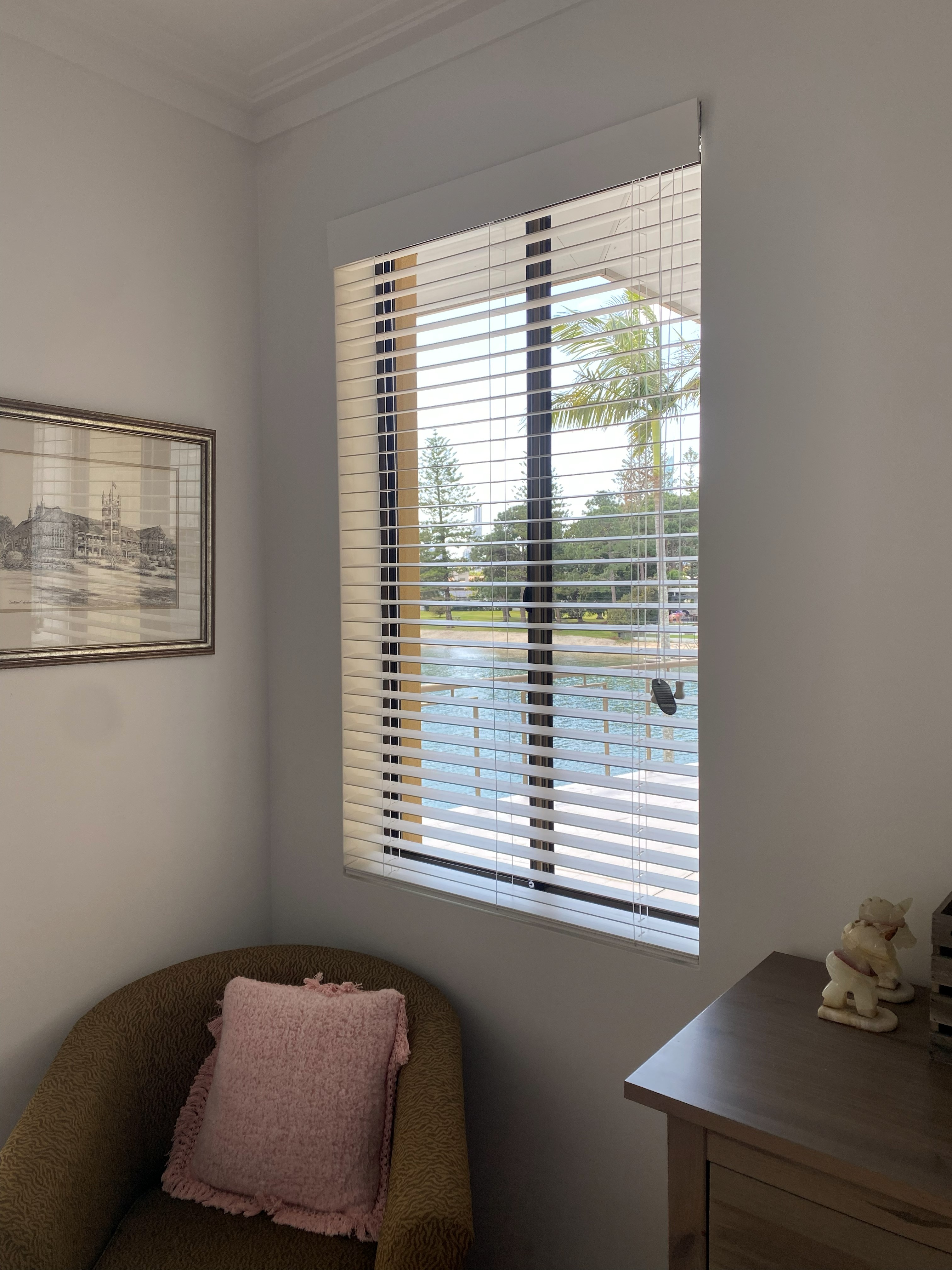 White venetian blinds fitted to a tall window with a river view
