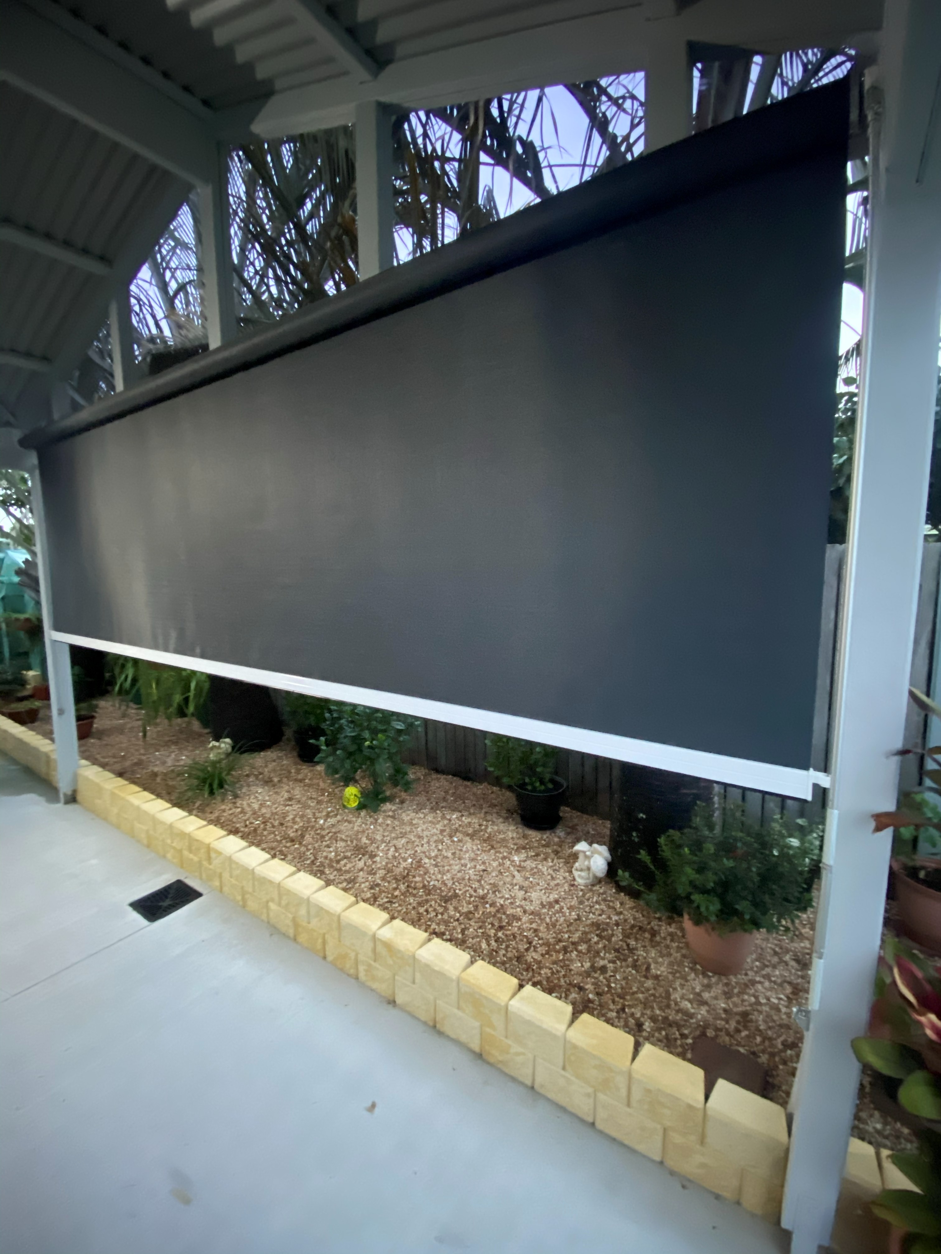 Wire guide outdoor blind fully lowered over an alfresco garden area