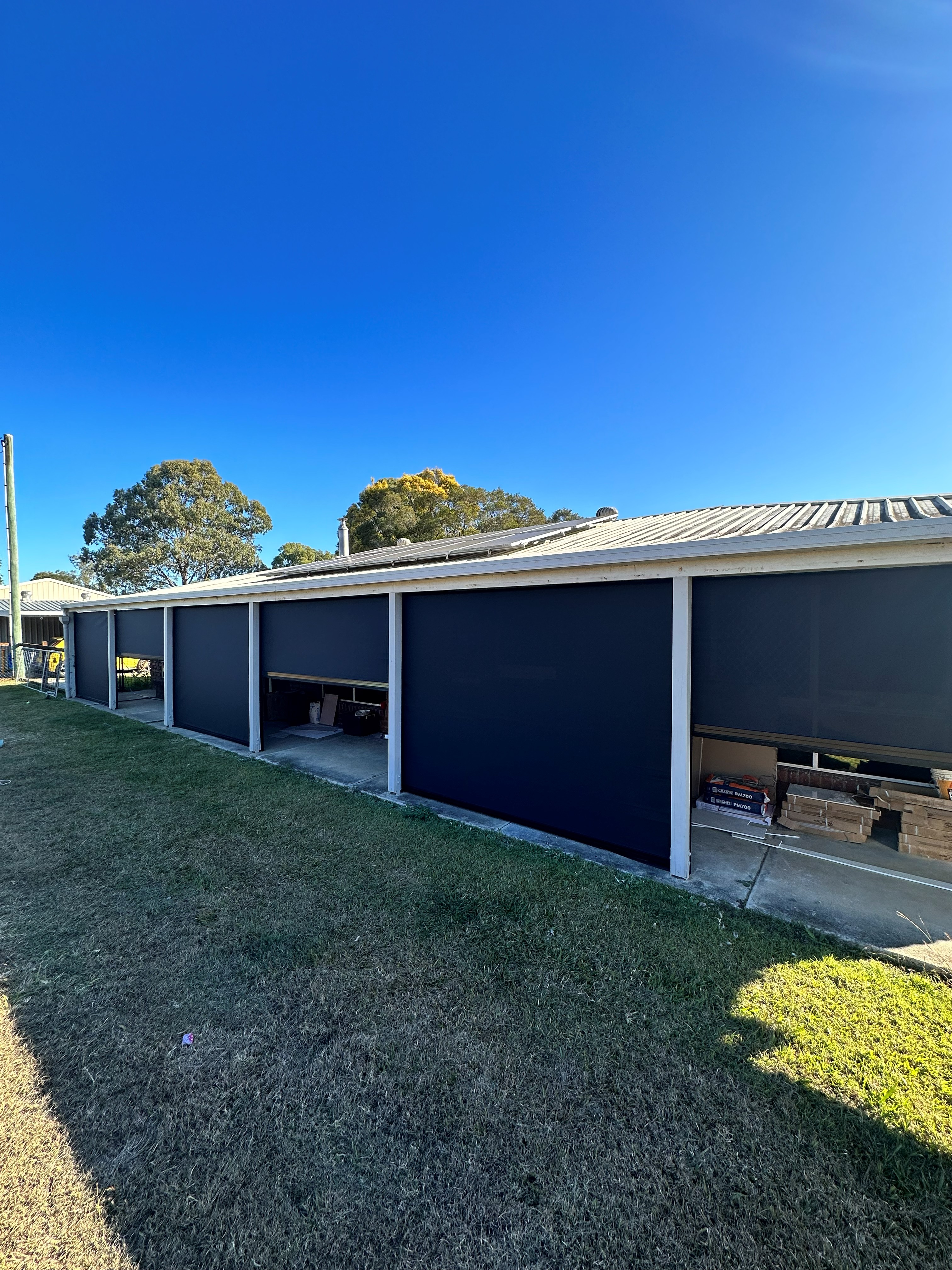 Zipscreen outdoor blinds along a tiled alfresco walkway with feature screen panel
