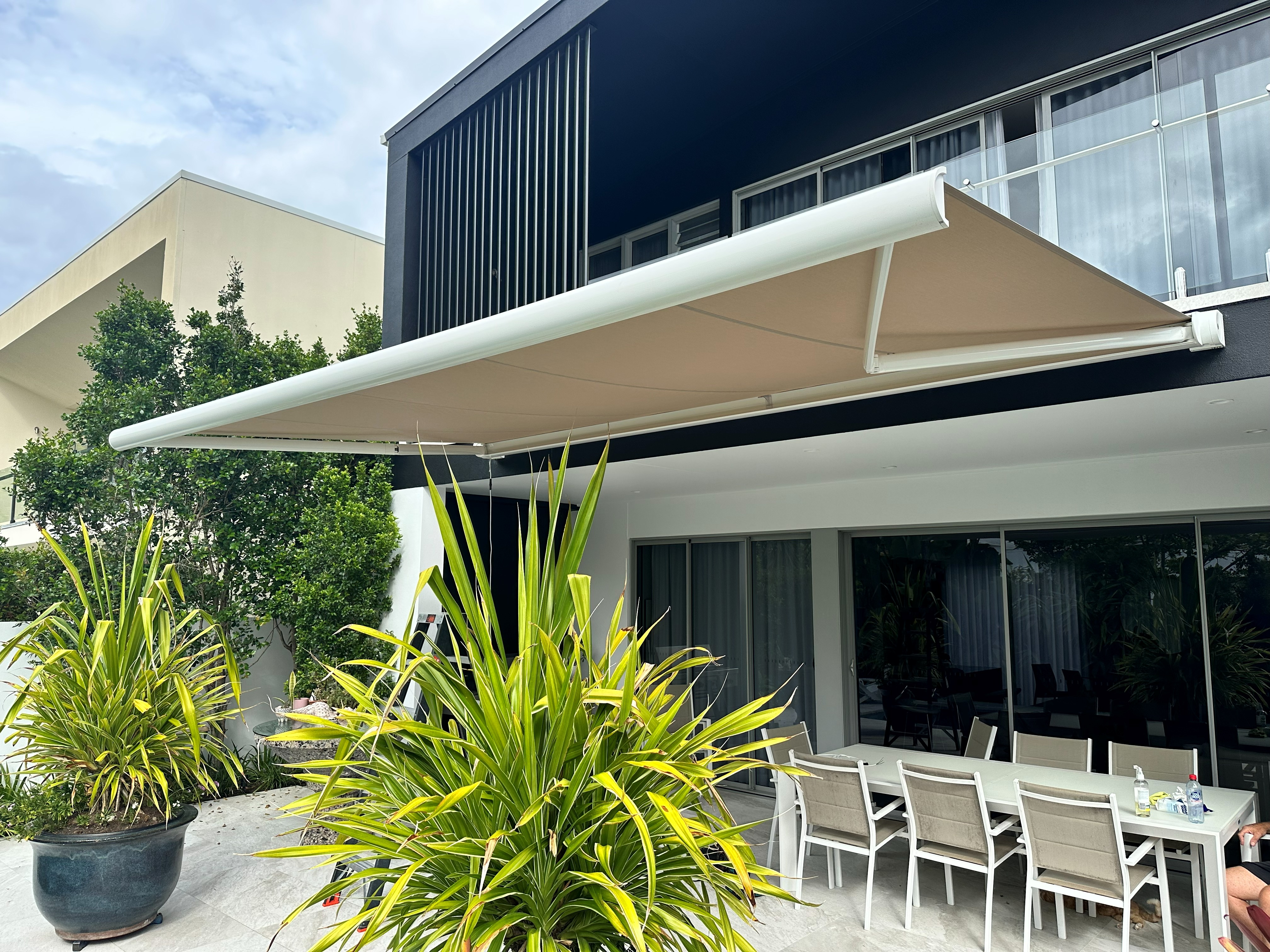 Folding arm awning extended over an outdoor alfresco dining area
